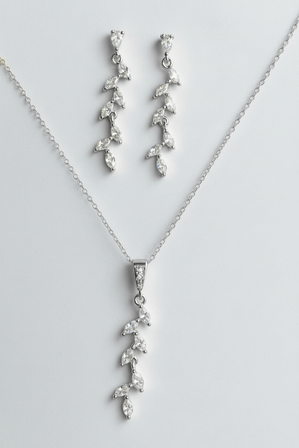 Silver cascading jewelry set photographed on reflective mirror surface