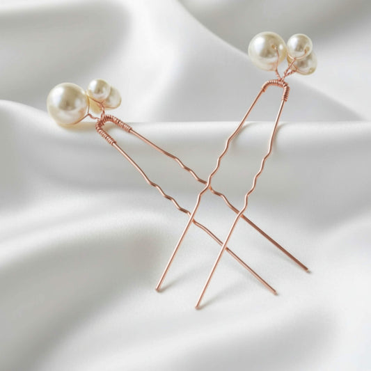 Elegant triple‑pearl wedding hair pins in gold, photographed on soft satin fabric.