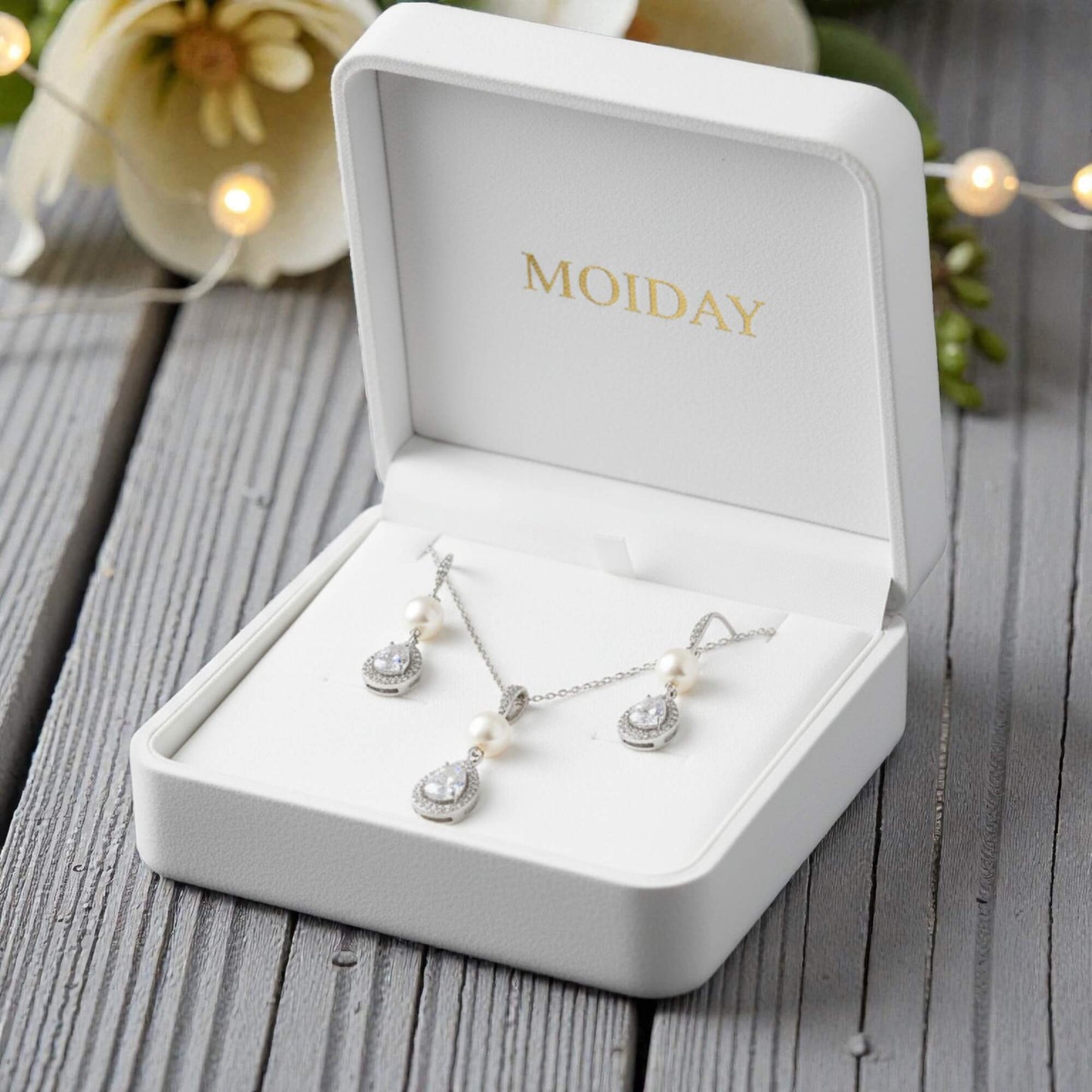 Bridal Jewelry set in a 'MOIDAD' box on a wooden surface with decorative lights in the background.