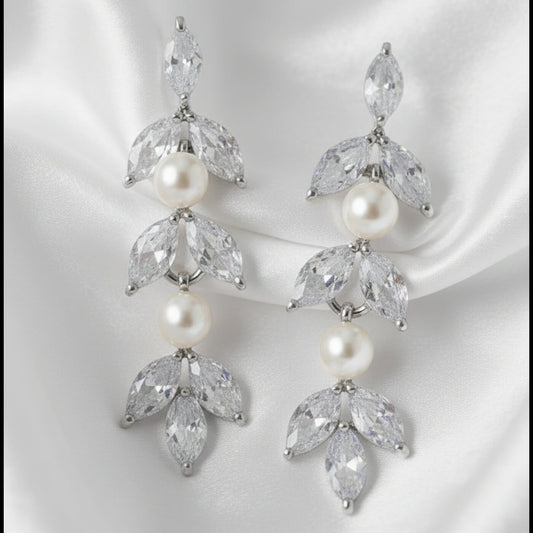 Pair of earrings with pearls and clear stones on a white background