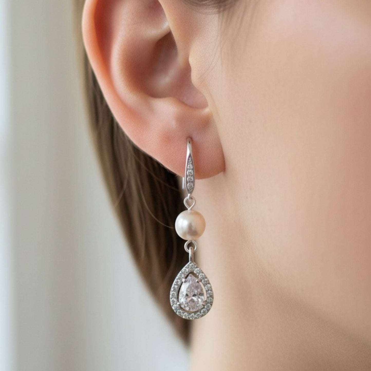Soft bridal close-up of bride wearing pearl teardrop earrings, warm natural lighting and elegant styling.