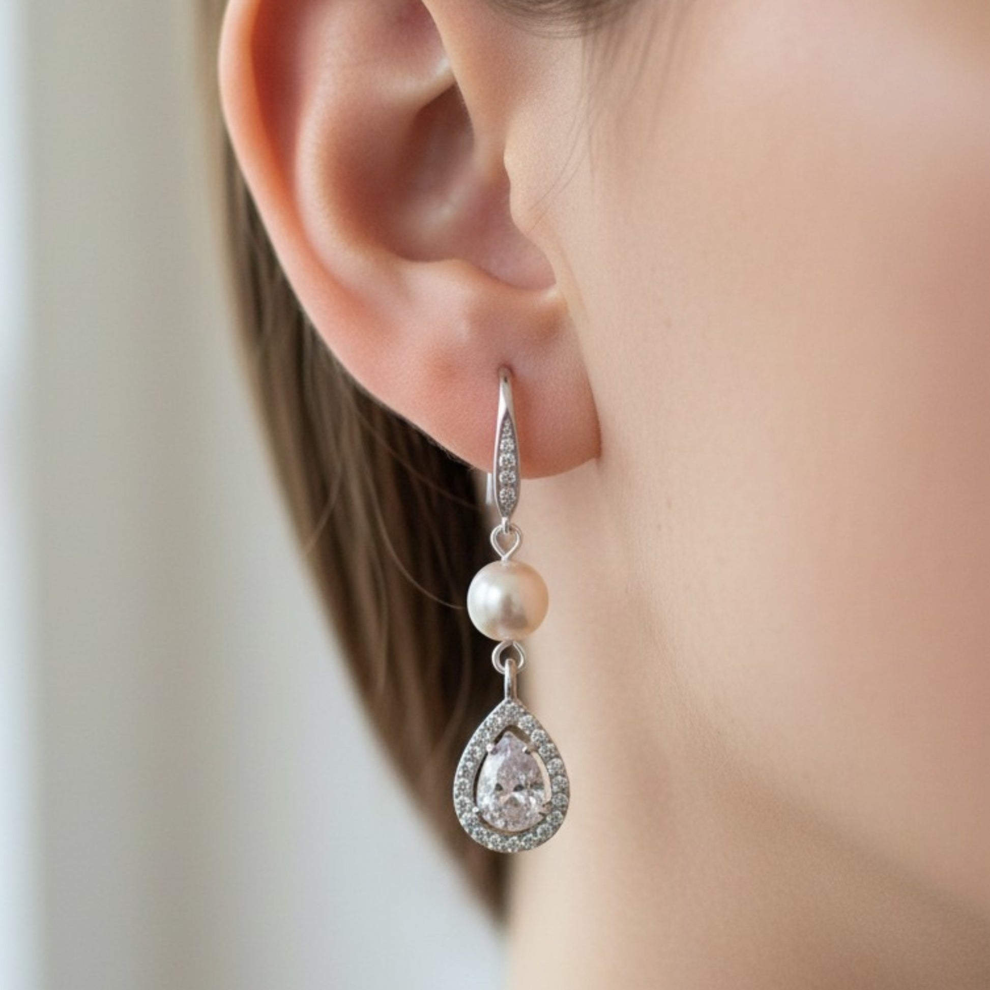 Soft bridal close-up of bride wearing pearl teardrop earrings, warm natural lighting and elegant styling.