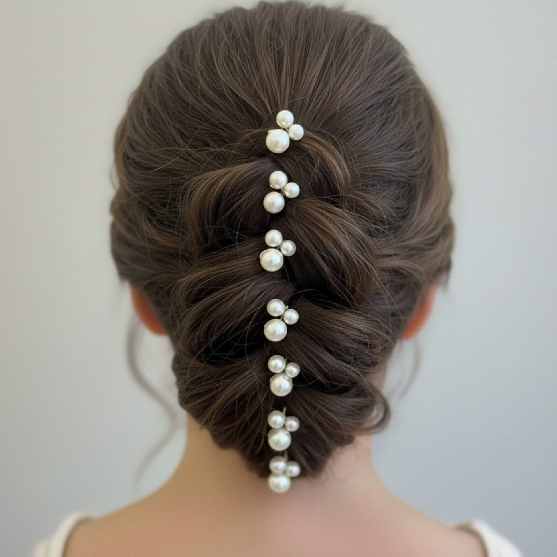 Bride with an elegant low bun adorned with pearl cluster hair pins on one side, soft natural light