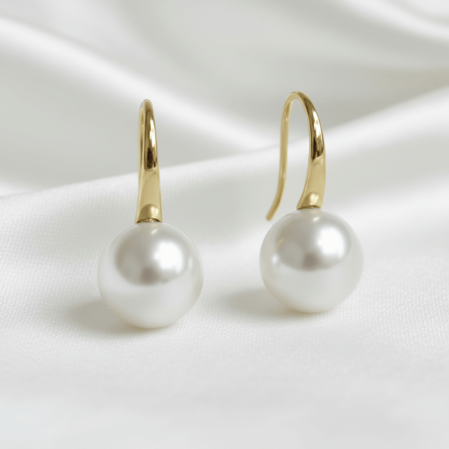 bridal Pearl earrings with gold hooks on a white satin background