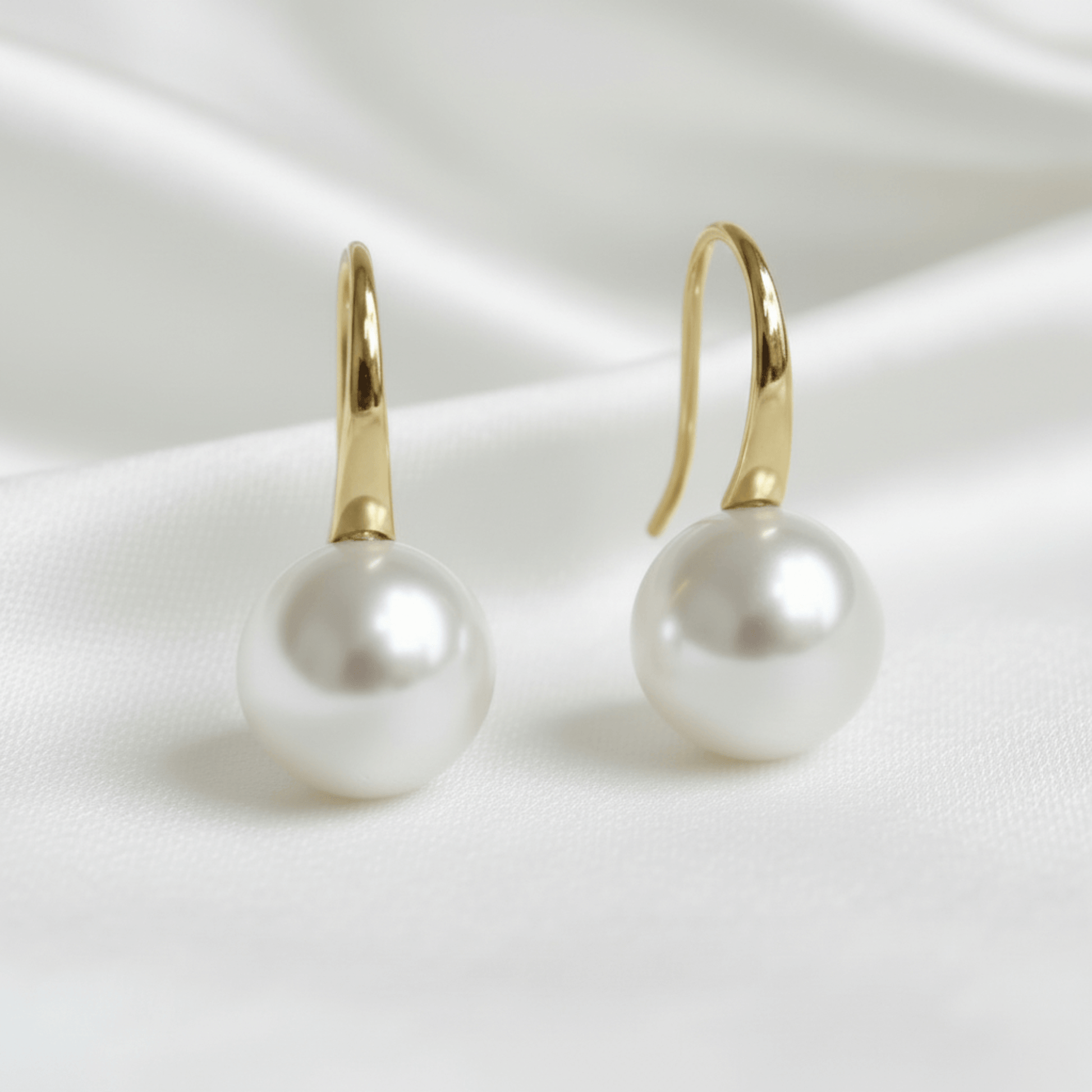 bridal Pearl earrings with gold hooks on a white satin background