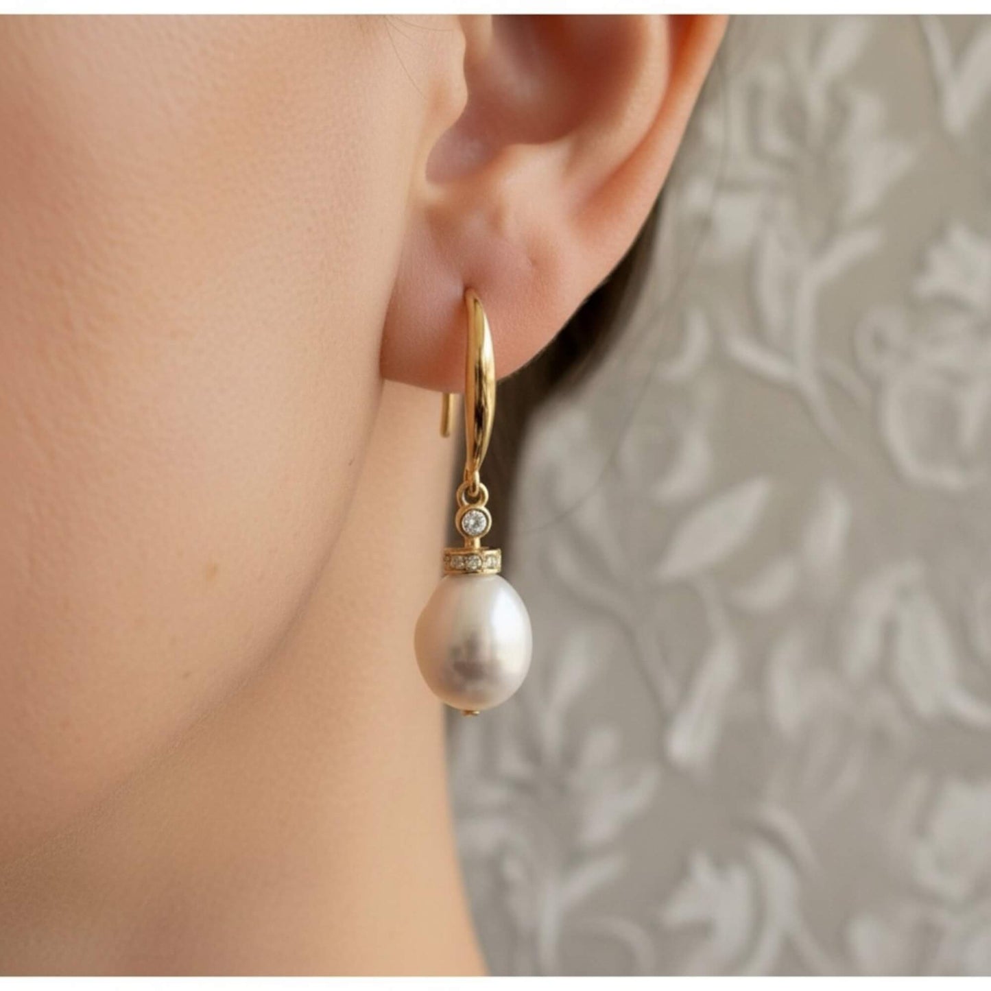 Close-up of bride wearing gold pearl drop earrings with zirconia accent, soft lighting and elegant bridal mood.