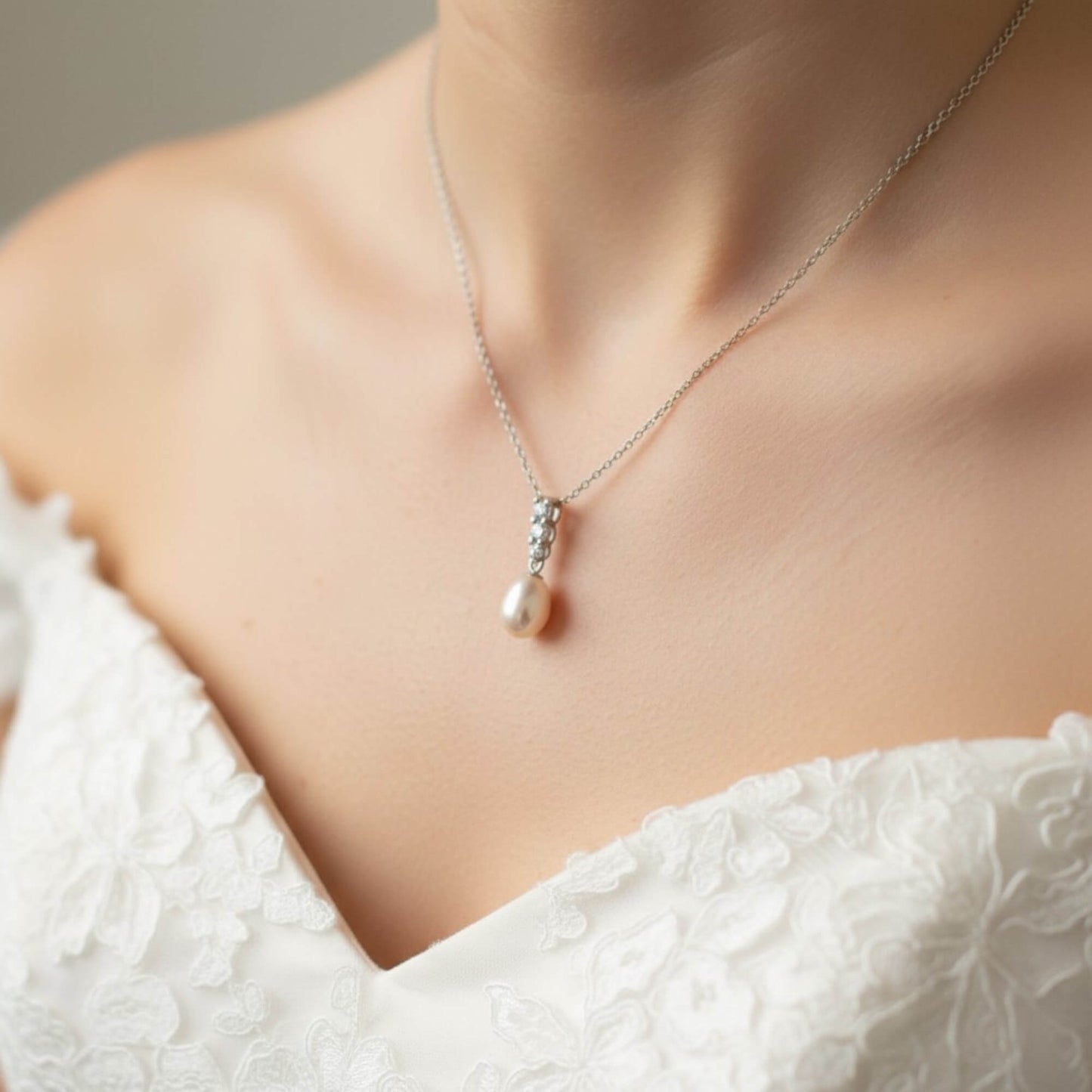 Bridal portrait focusing on silver pearl drop necklace against white gown, soft natural light, premium Australian bridal jewellery.