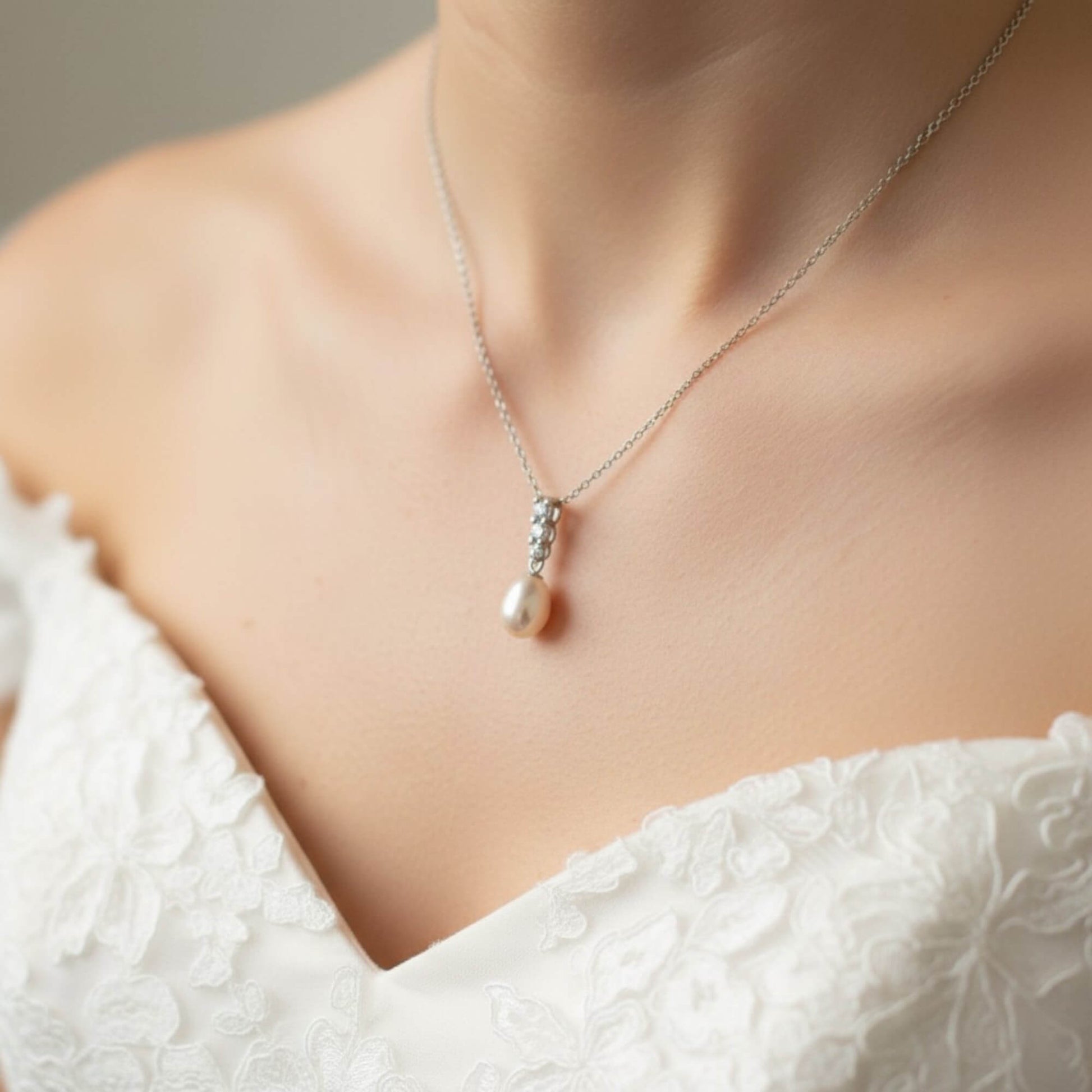 Bridal portrait focusing on silver pearl drop necklace against white gown, soft natural light, premium Australian bridal jewellery.