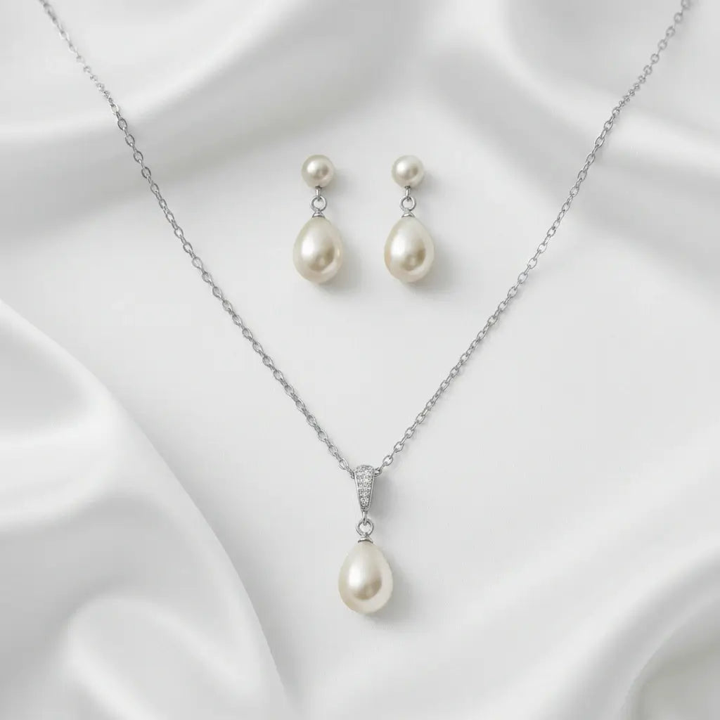 Pearl necklace and earrings set on a white fabric background