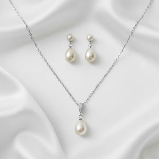 Pearl necklace and earrings set on a white fabric background