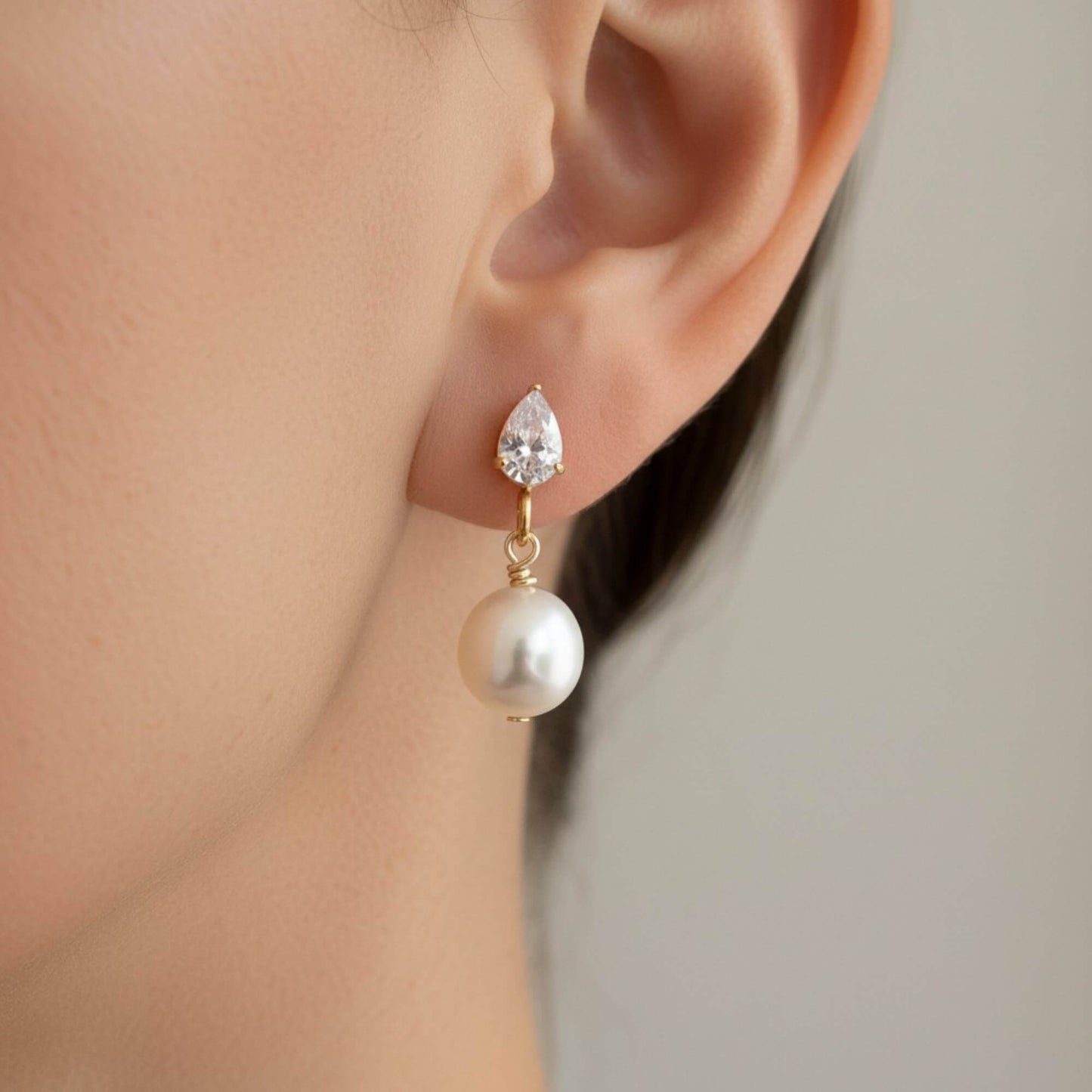 lose-up of bride’s profile showing gold and pearl drop earrings, minimal makeup, soft airy lighting.