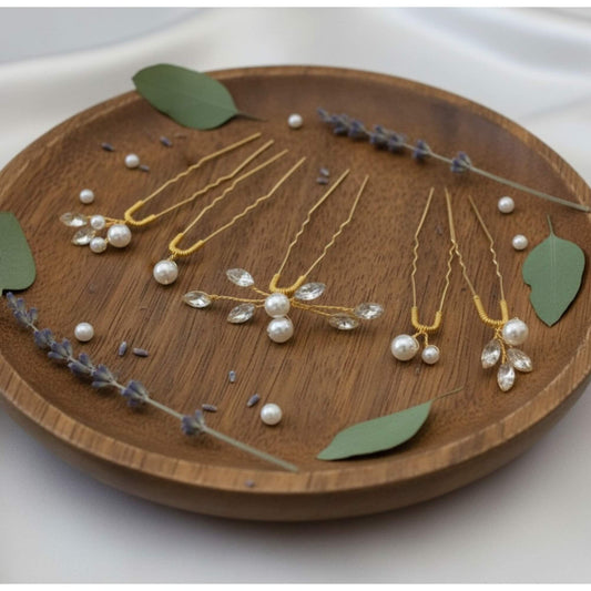 Delicate gold bridal hair pins with pearls and crystals styled on wood
