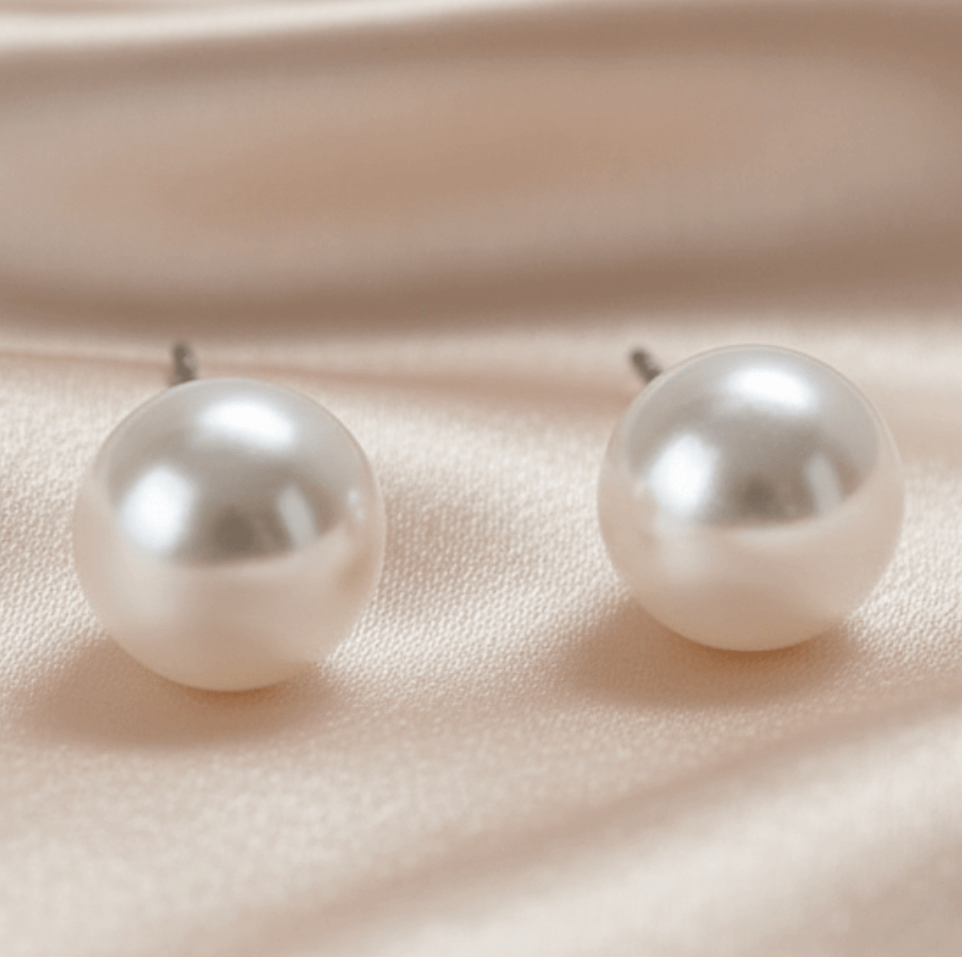 Pair of pearl earrings on a soft pink background