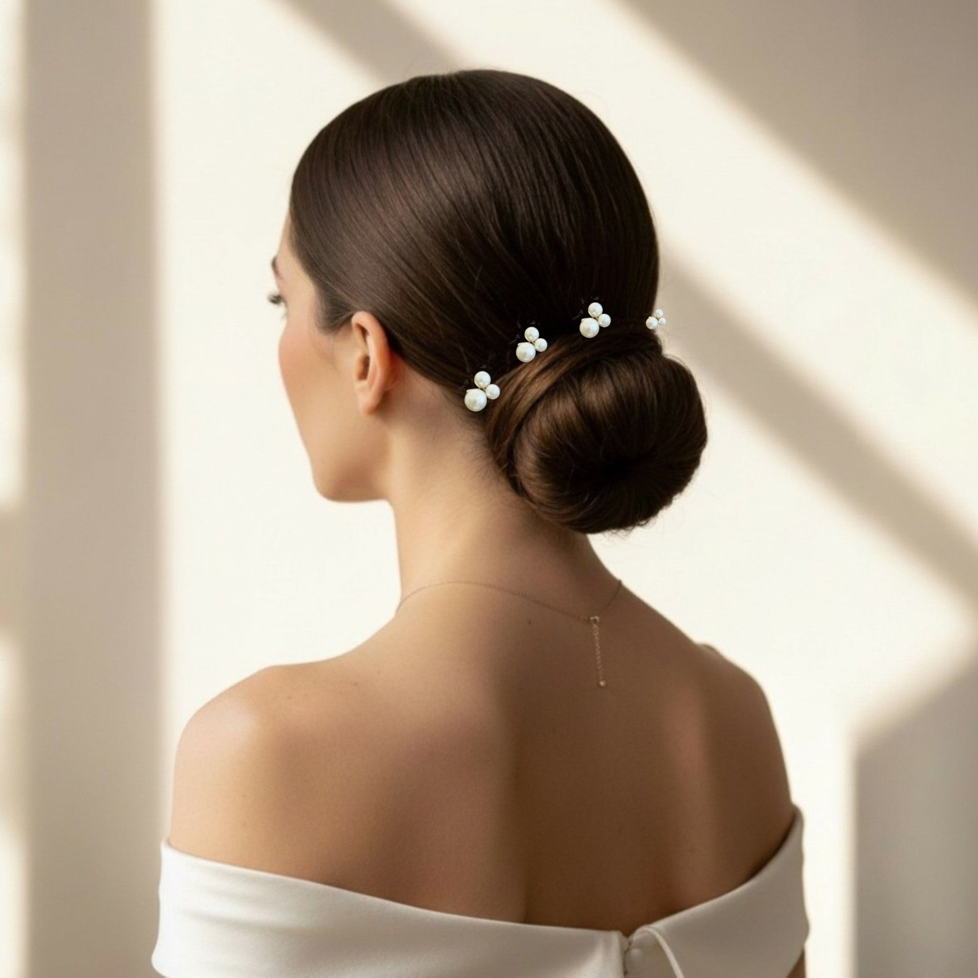 Bride with a stylish hair bun wearing a pearl hair accessory against a neutral background