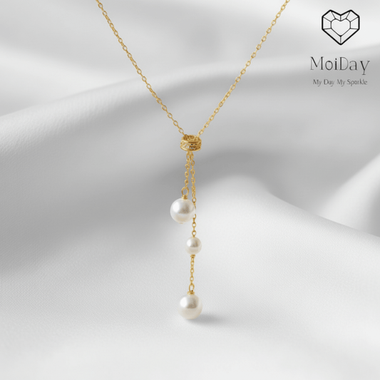 Pearl necklace with gold chain on a white fabric background, featuring the brand 'MoiDay'.