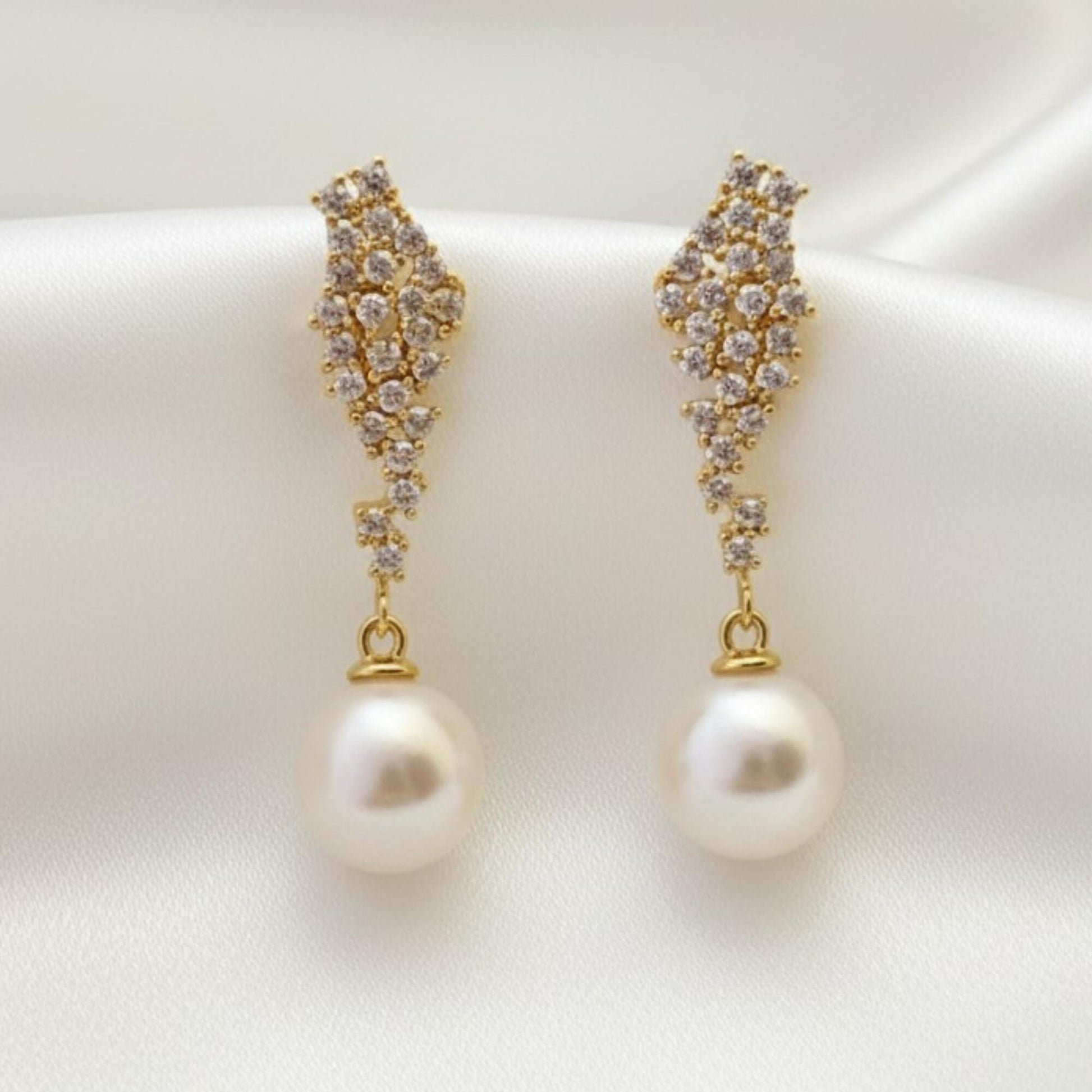 Gold crystal‑accent pearl drop earrings displayed on cream satin, elegant bridal jewellery for Australian weddings.