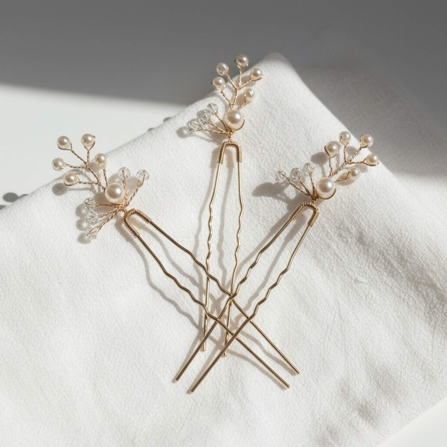 Gold hair pins featuring delicate pearl clusters and crystal accents styled on a clean white background.