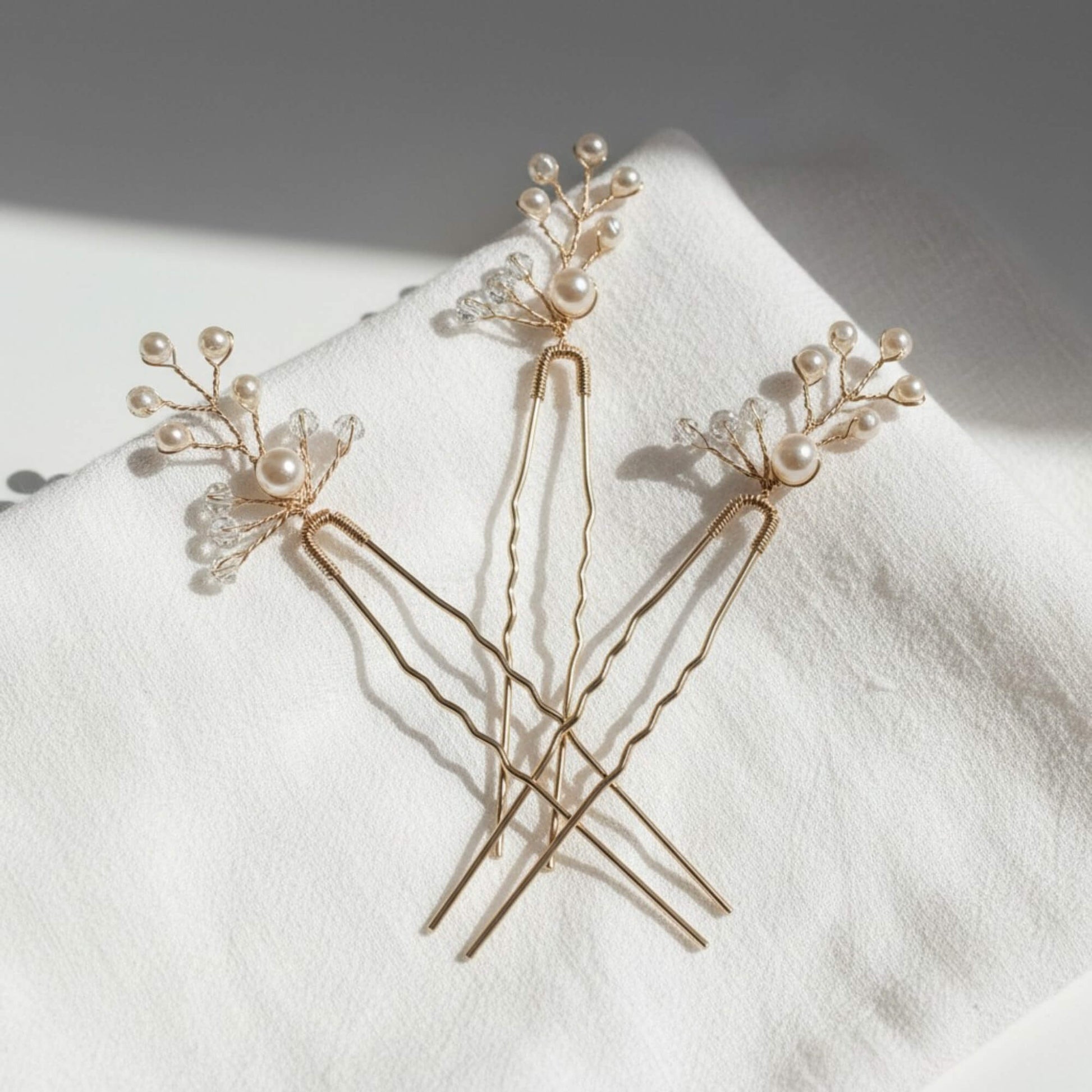 Gold hair pins featuring delicate pearl clusters and crystal accents styled on a clean white background.