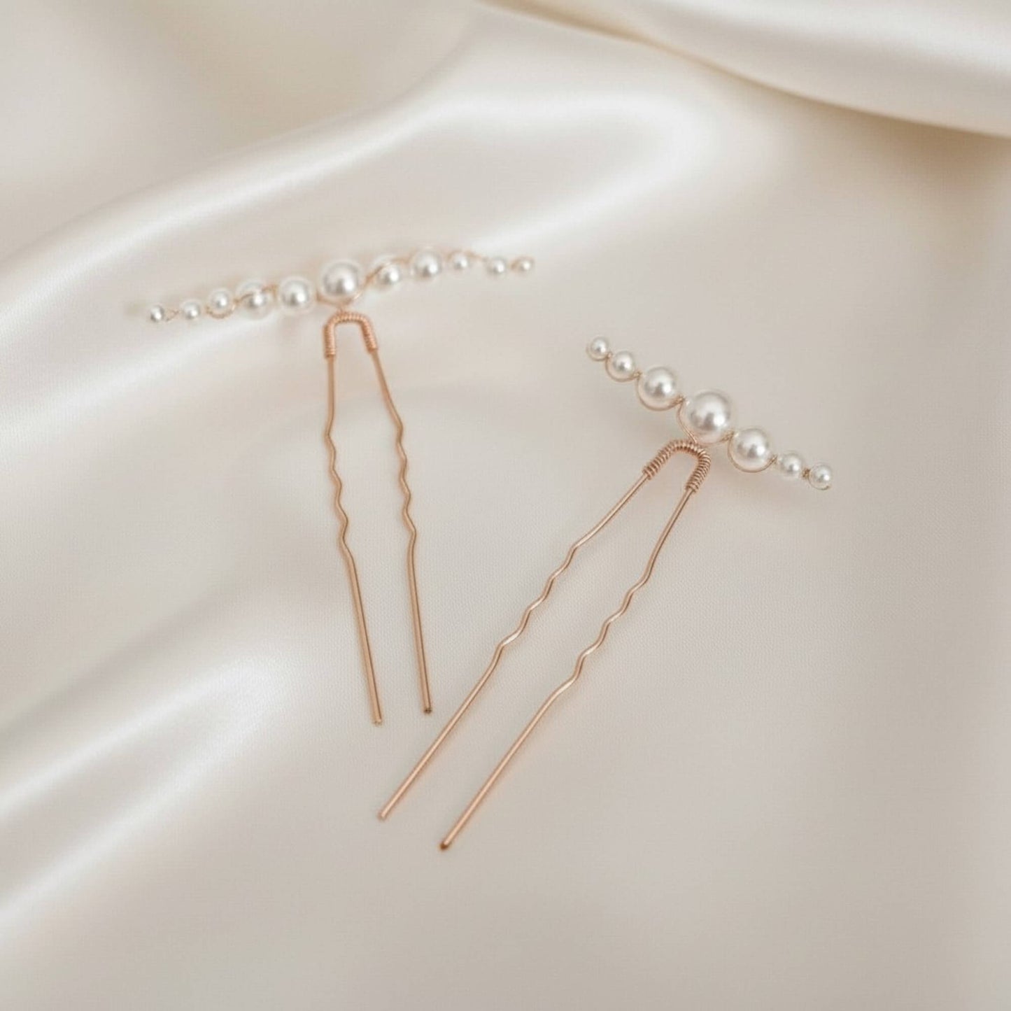 Rose gold bridal hair pin with organic pearl arrangement photographed on soft satin.