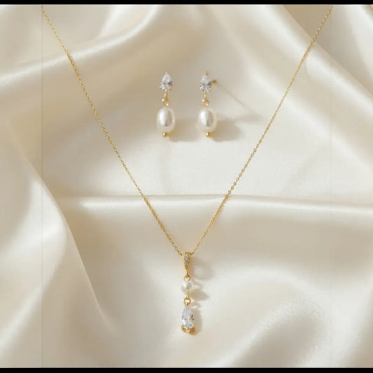 Gold necklace and earrings with pearls on a beige fabric background