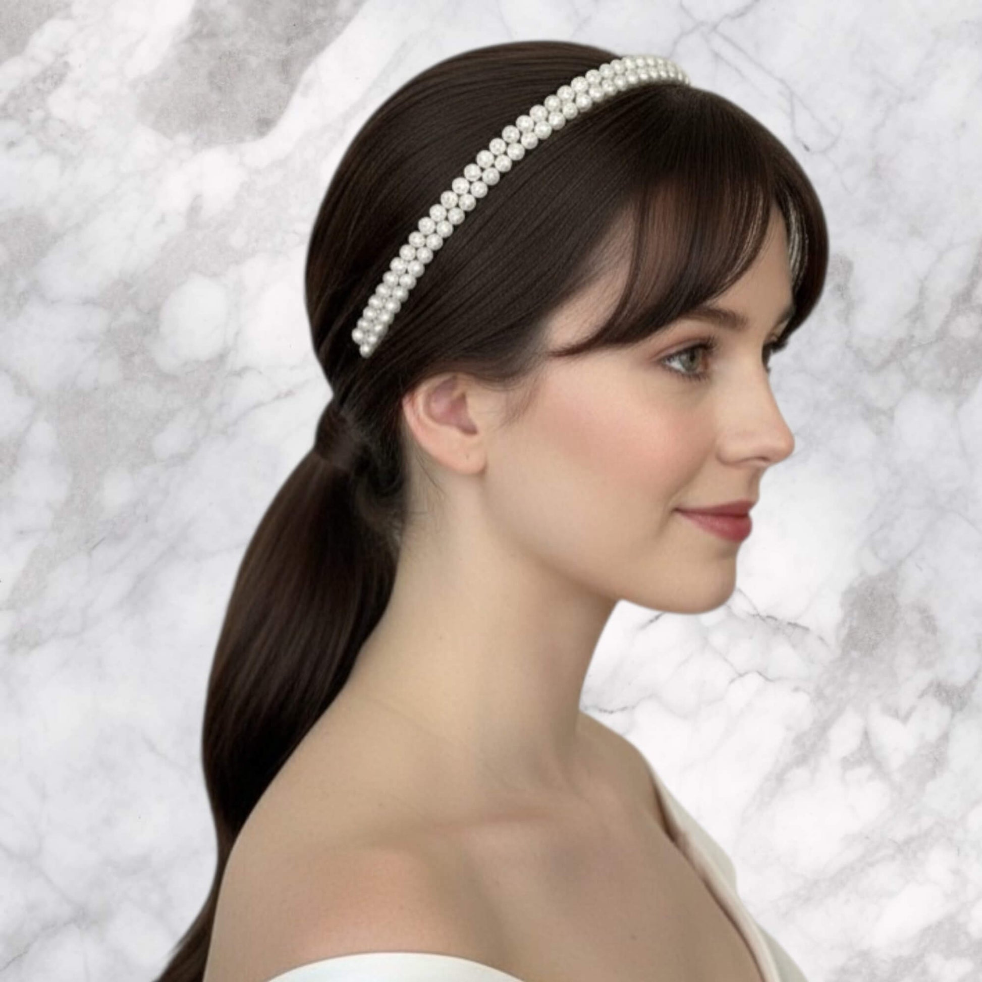 Side angle view of a gold-finish bridal headband featuring double rows of soft‑white glass pearls.