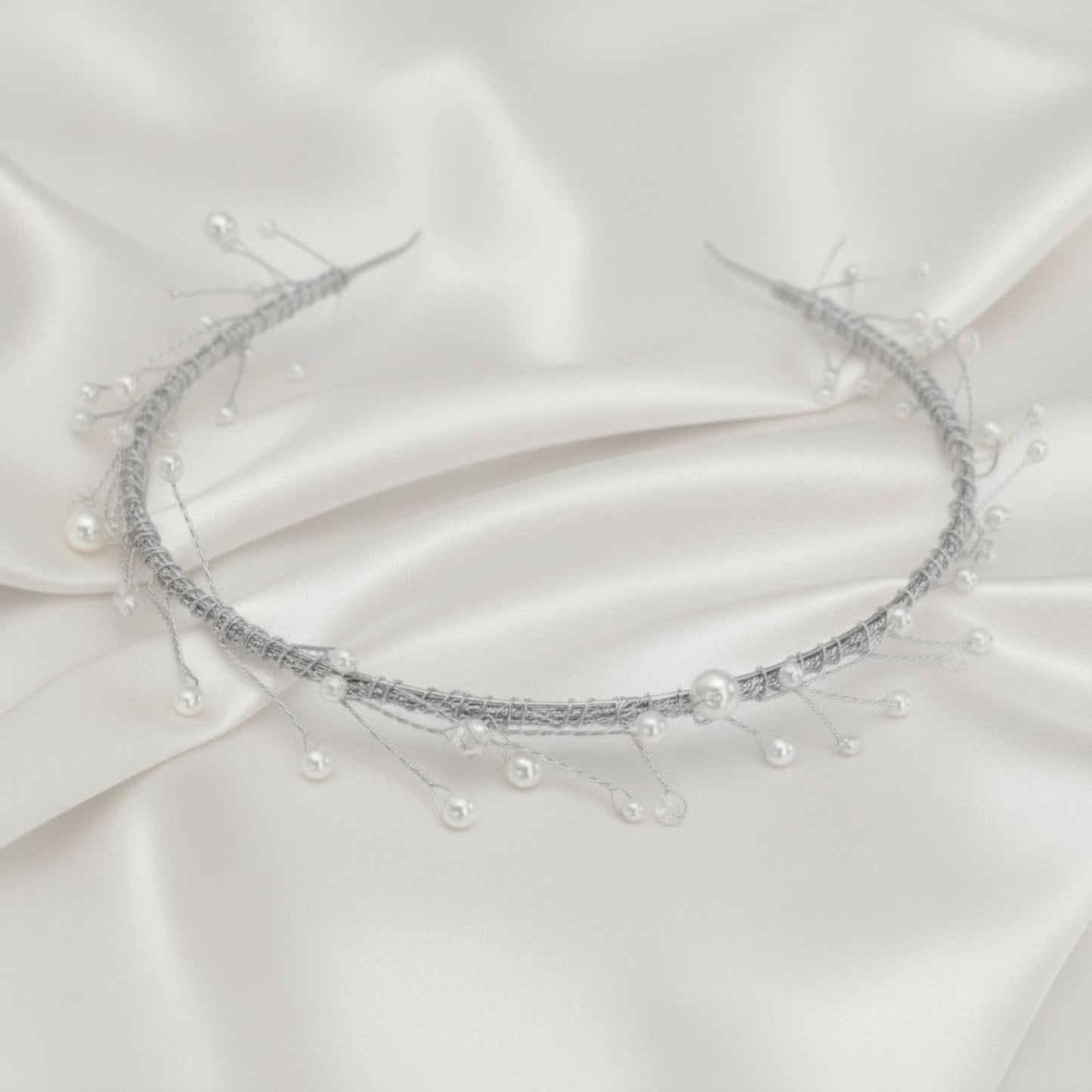 Delicate bridal hairvine with white pearls and clear crystals on white satin.