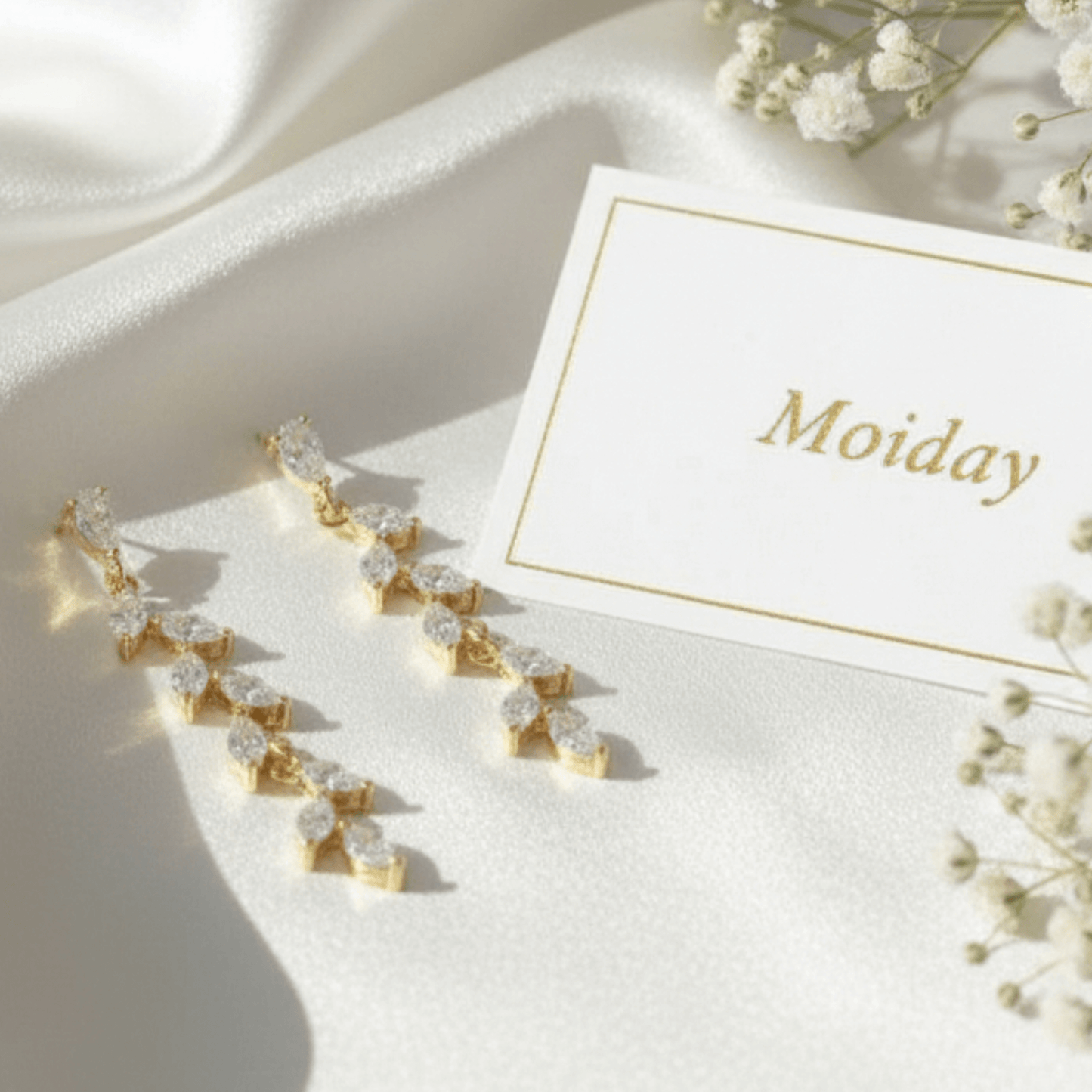 Gold teardrop earrings photographed on neutral wedding setting