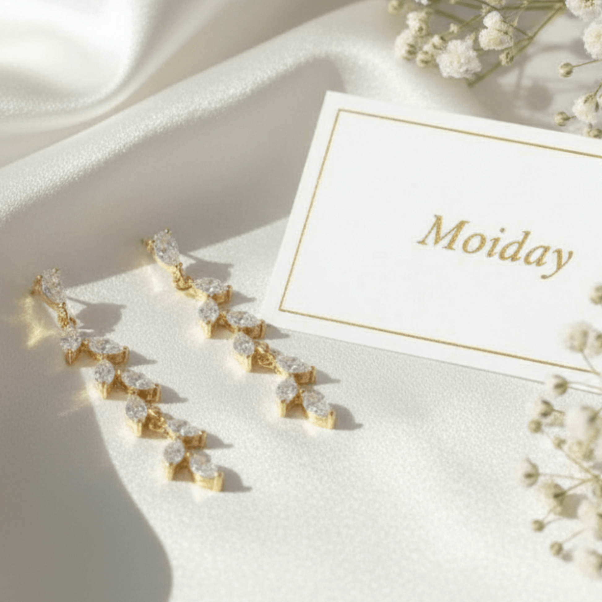 Gold teardrop earrings photographed on neutral wedding setting