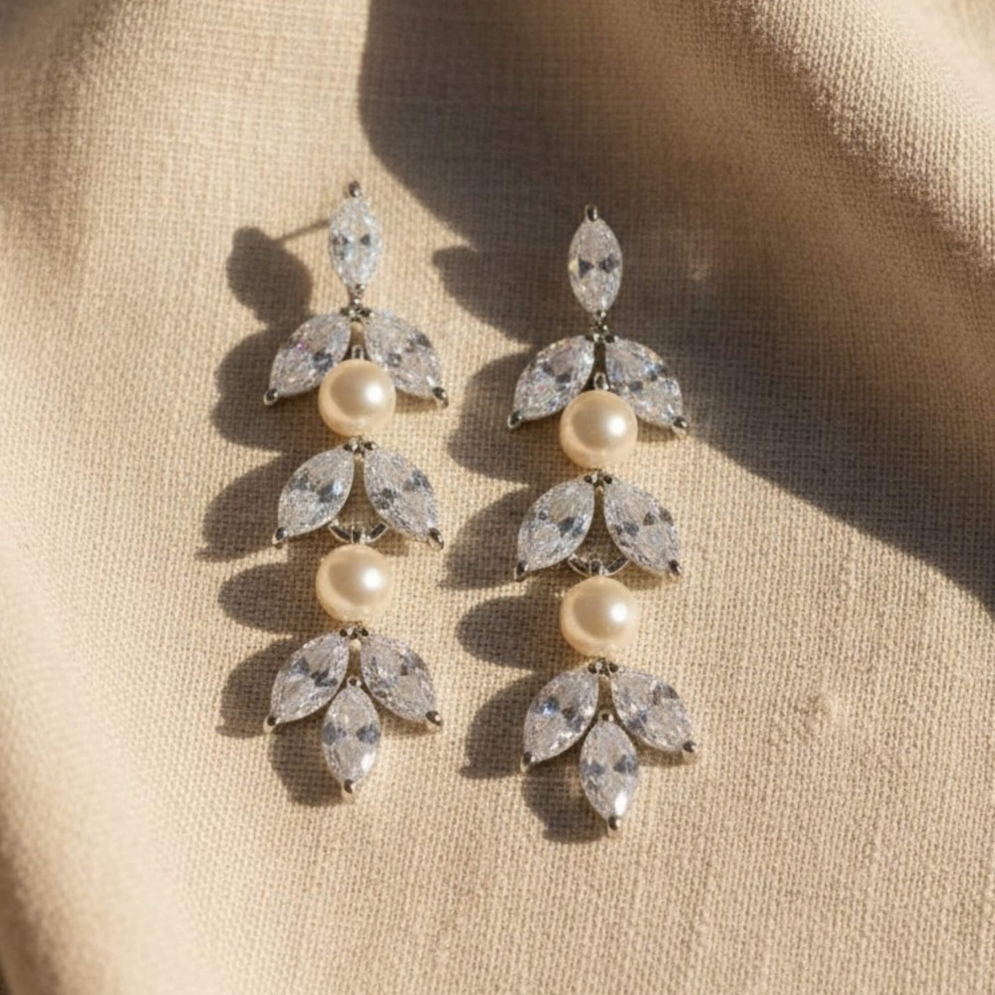 Side profile of bride with low bun wearing elegant pearl and crystal earrings, quiet luxury bridal mood.