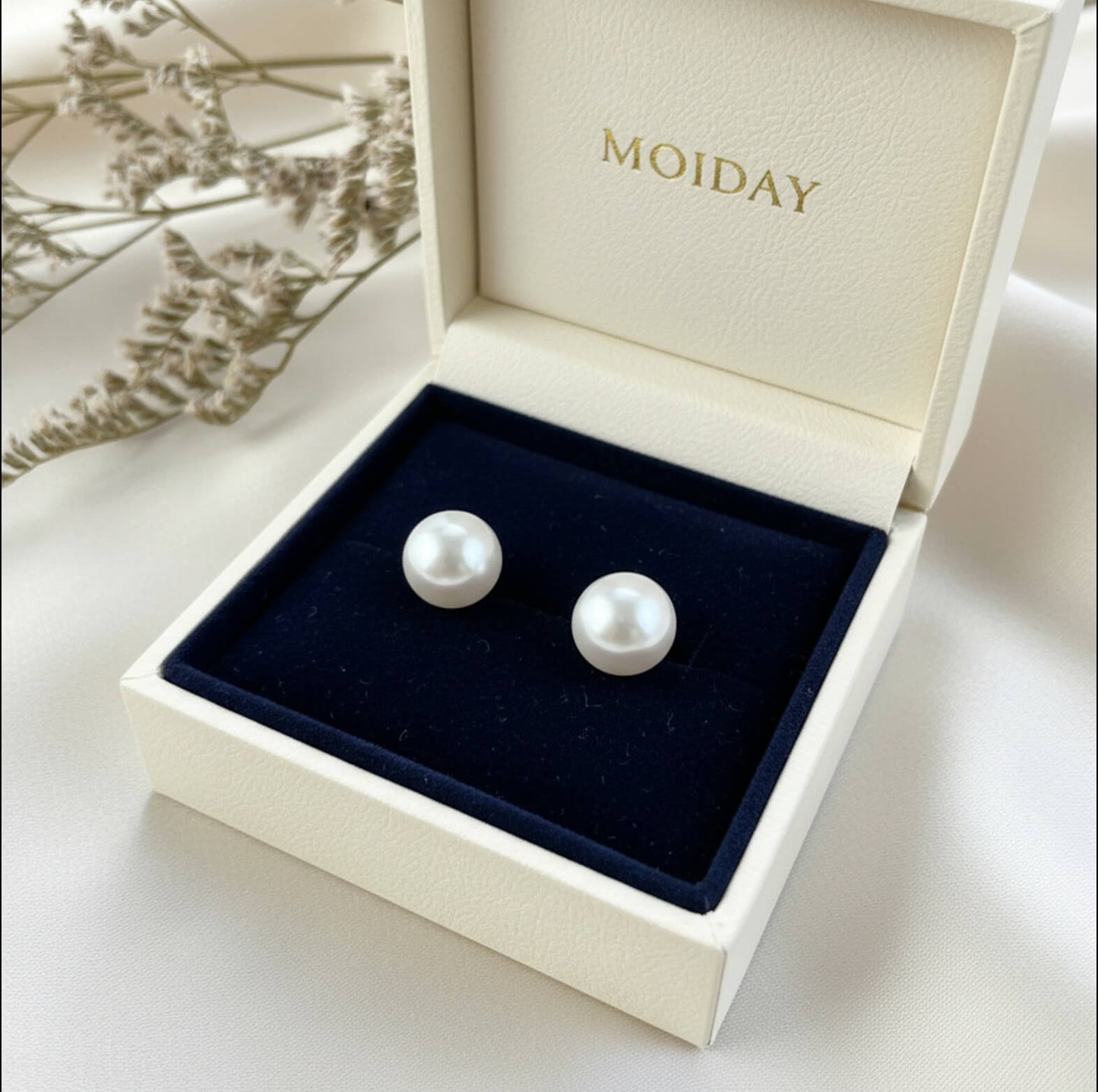 S925 silver pearl studs photographed on textured white surface