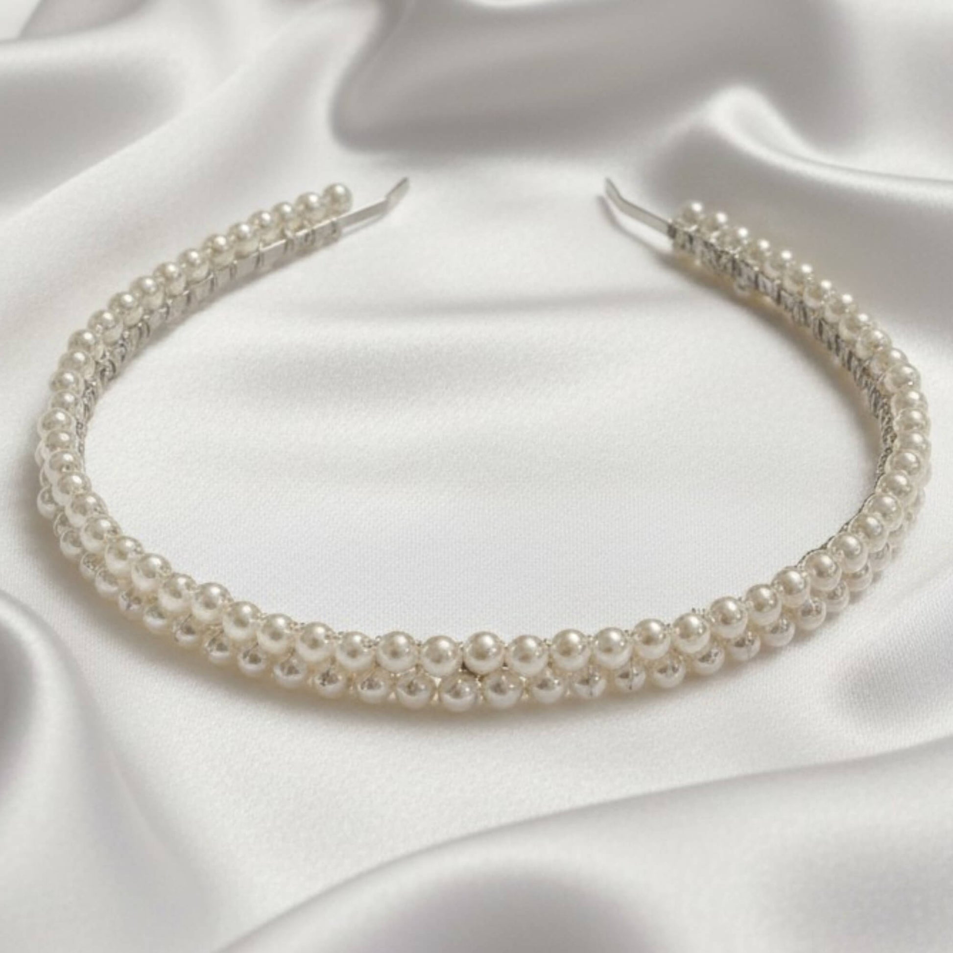 Bride looking down while wearing a modern double‑row pearl headband in soft white.