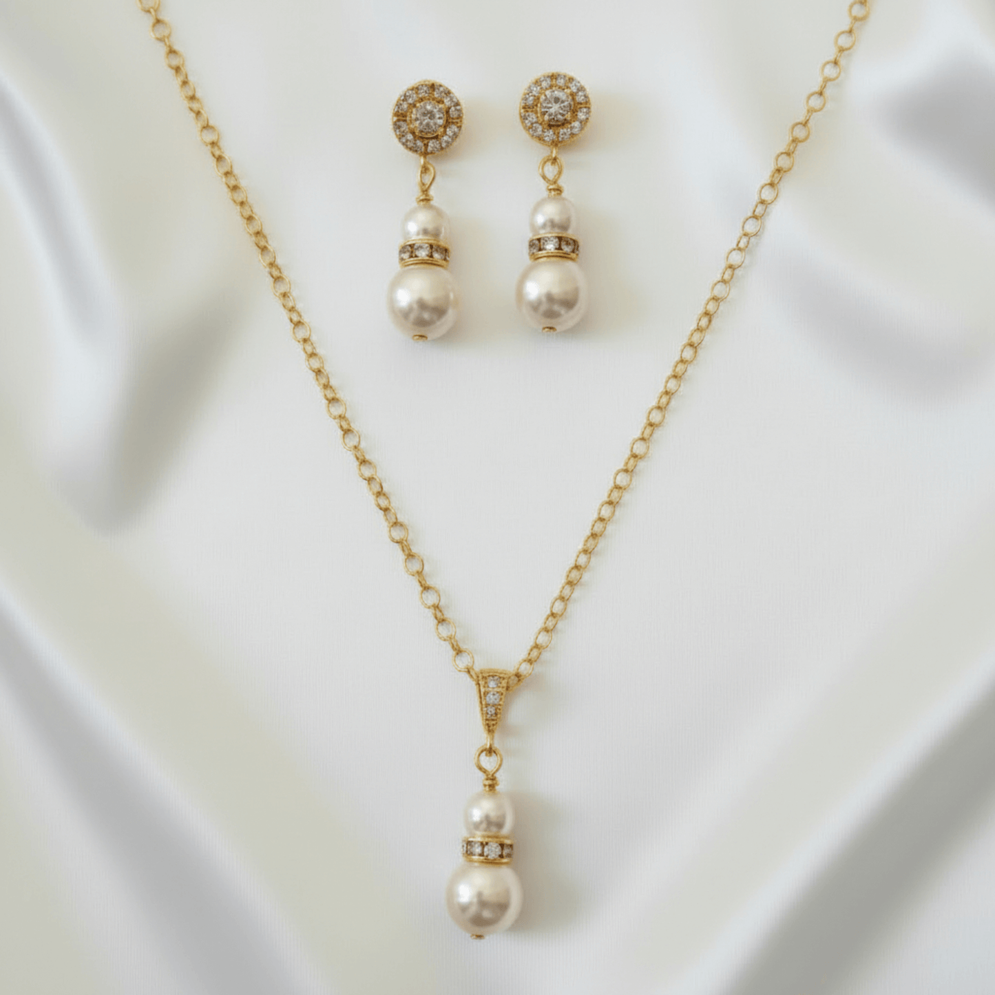 Pearl necklace and earrings set on a white fabric background