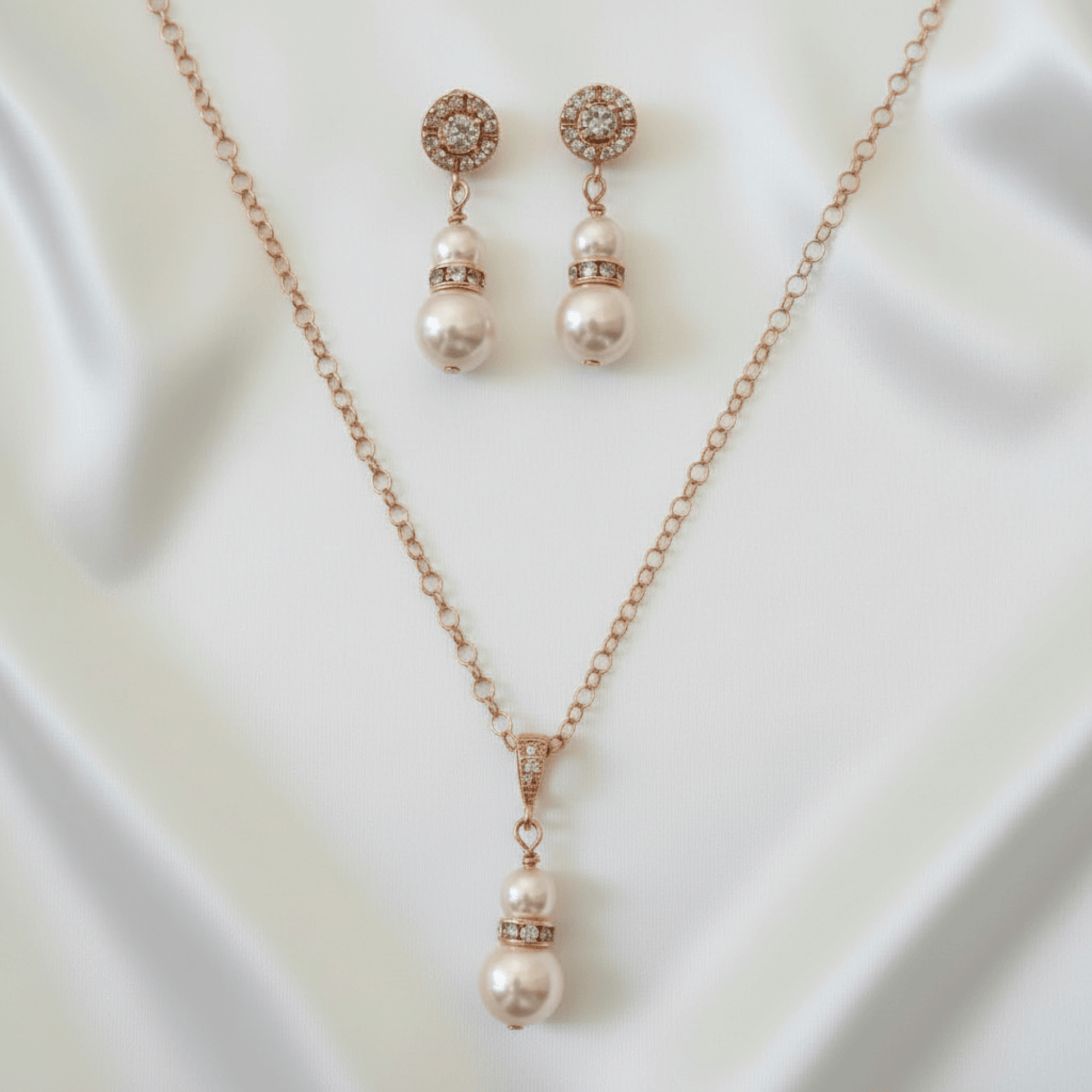 Pearl necklace and earrings set on a white fabric background