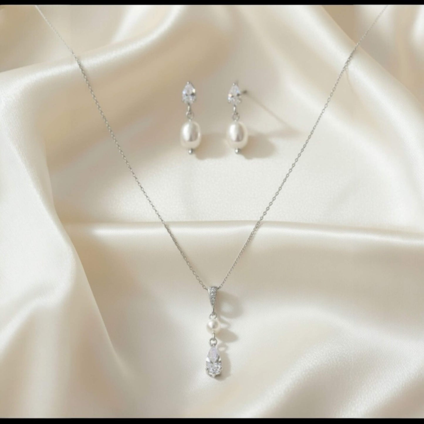 Silver necklace and earrings on a beige fabric background