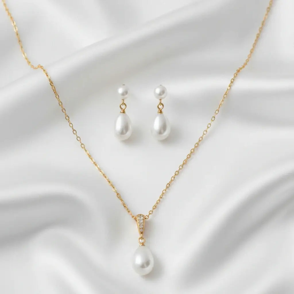 Silver teardrop pearl bridal necklace and earrings set displayed on white satin, soft natural lighting, elegant and minimal