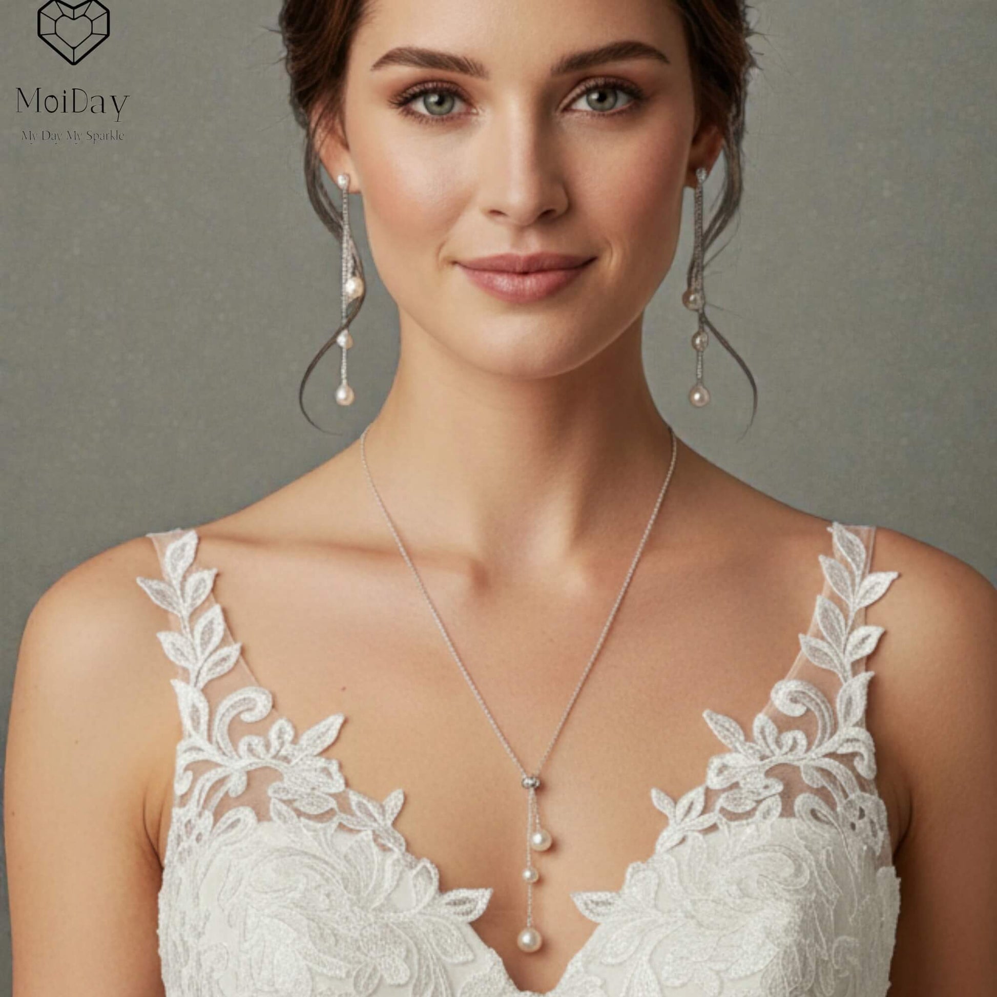 Woman wearing a white lace dress with a necklace and earrings against a gray background