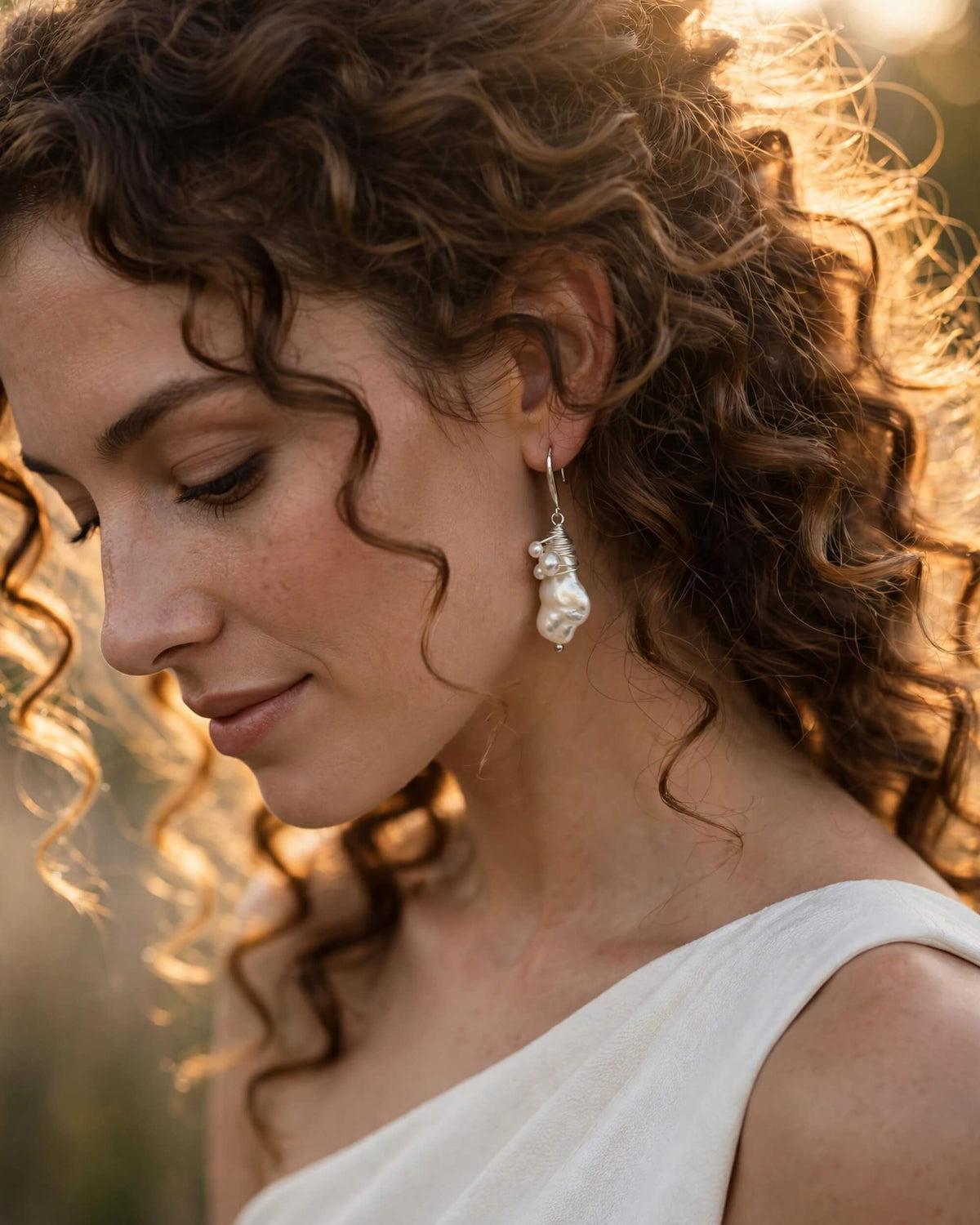side view of bride with baroque pearl dangle earrings accenting soft bridal updo