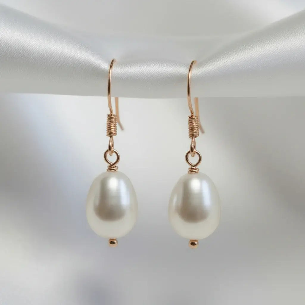 Pearl earrings with gold hooks on a light gray background
