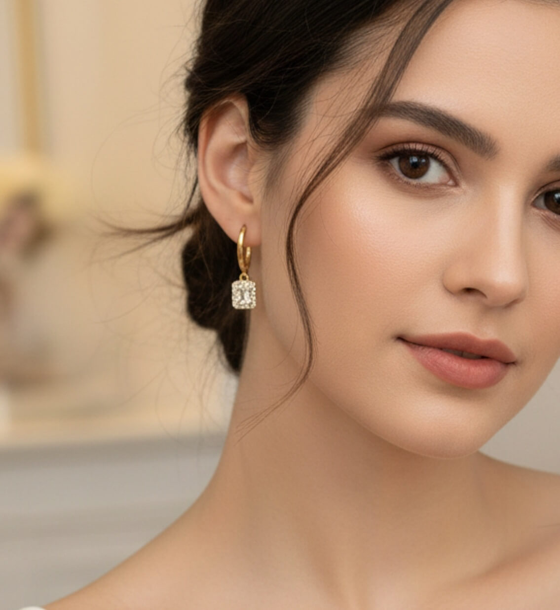 Close-up of a woman wearing gold hoop earrings with a neutral background