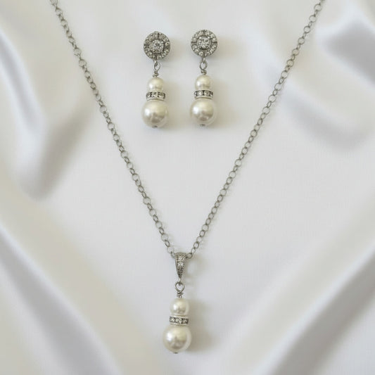 Pearl necklace and earrings set on a white fabric background