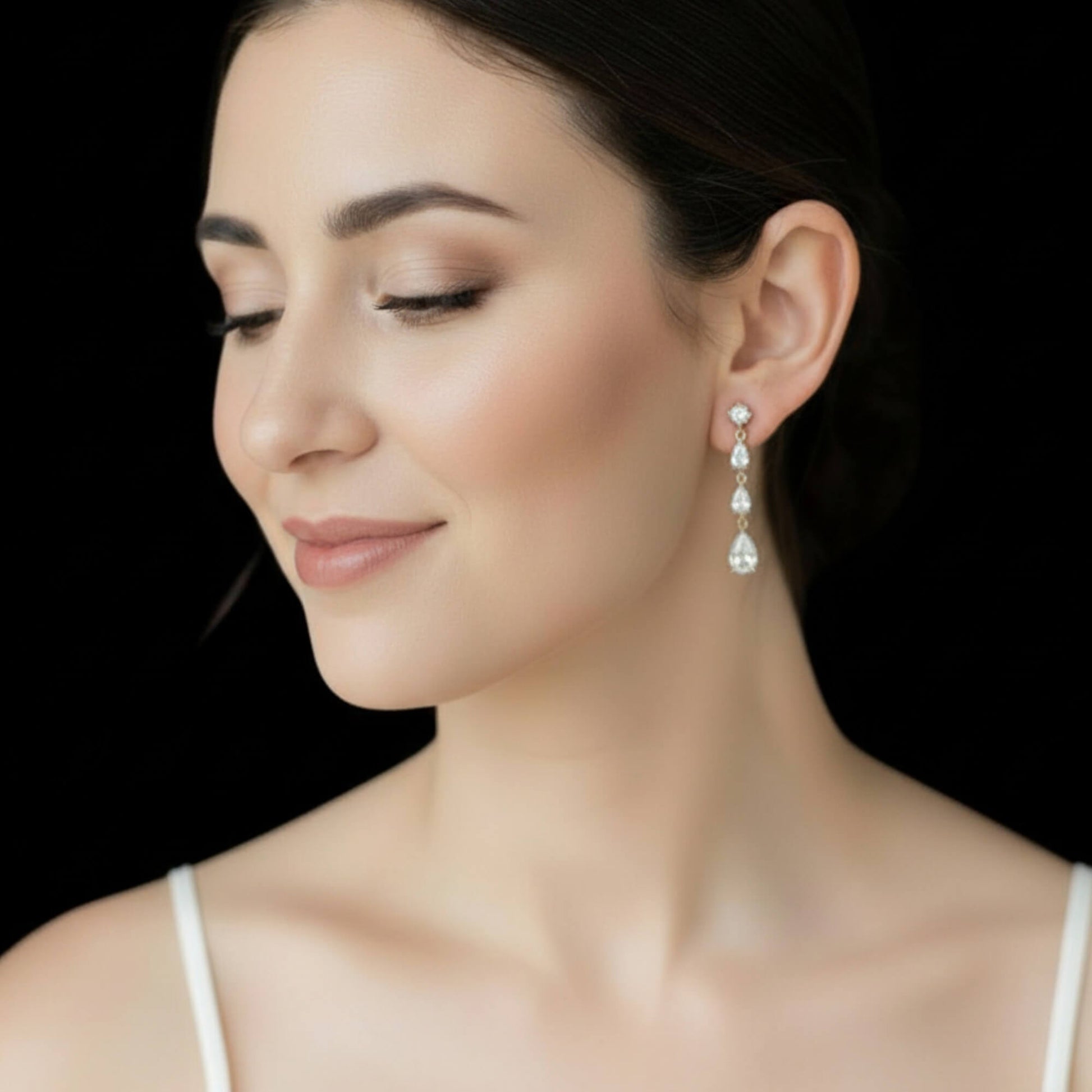 Woman wearing a pair of diamond earrings against a black background