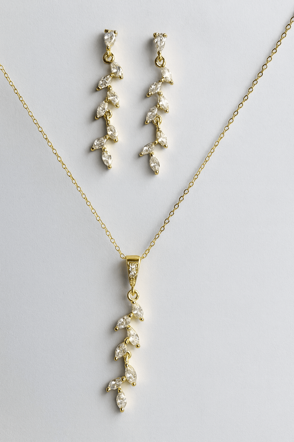 Gold leaf drop earrings photographed on bright neutral surface