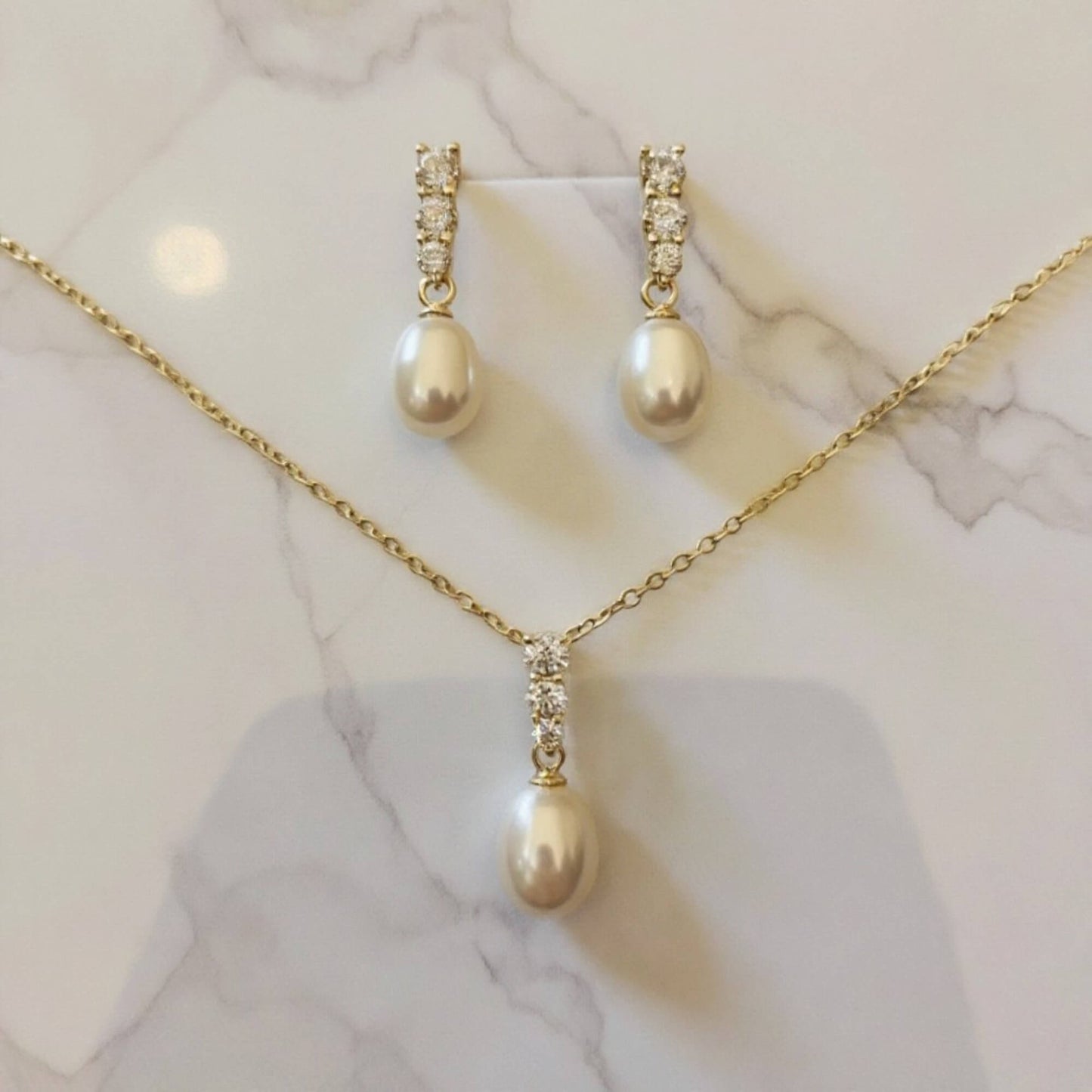 Minimalist pearl bridal jewellery set featuring teardrop pearls and crystal details.