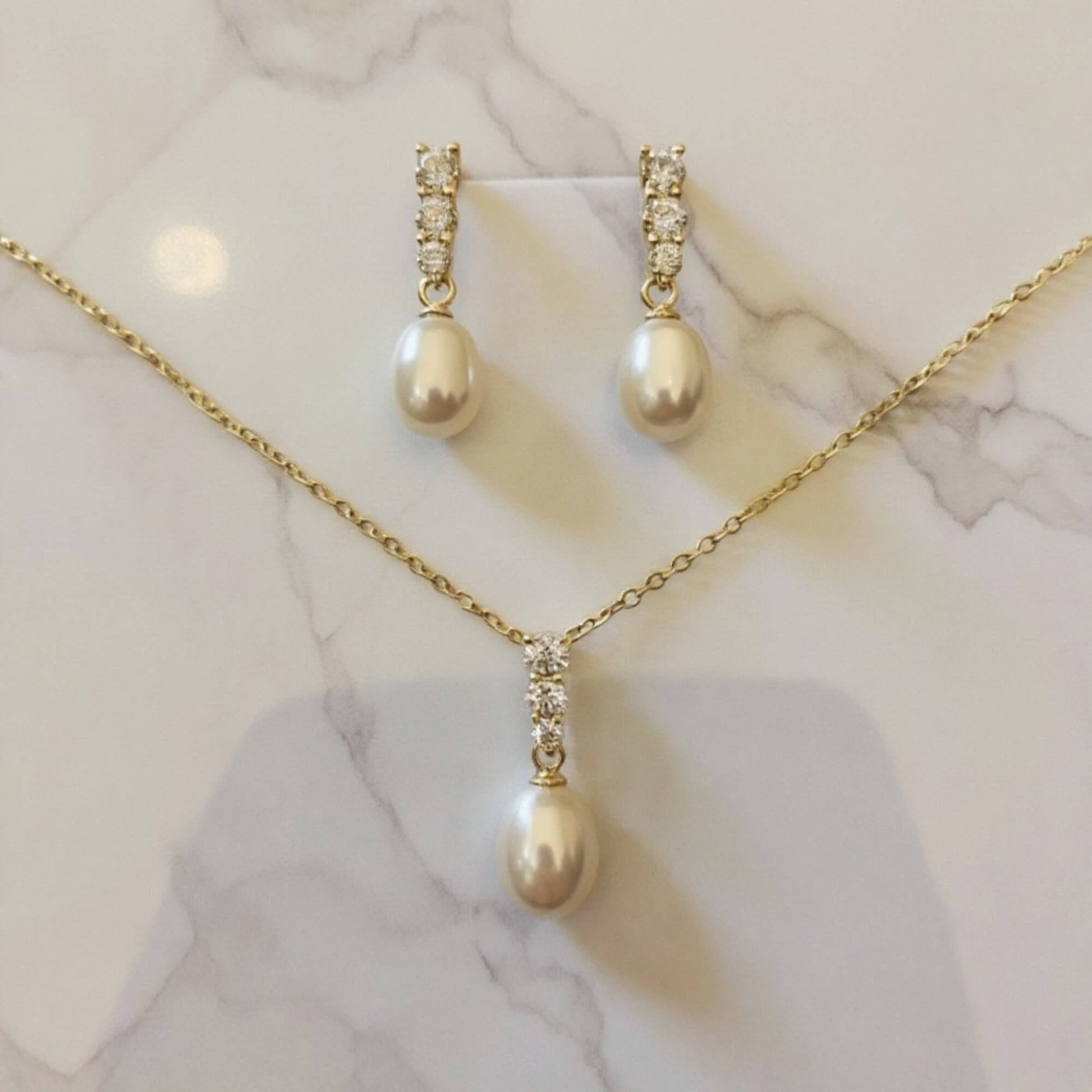 Minimalist pearl bridal jewellery set featuring teardrop pearls and crystal details.