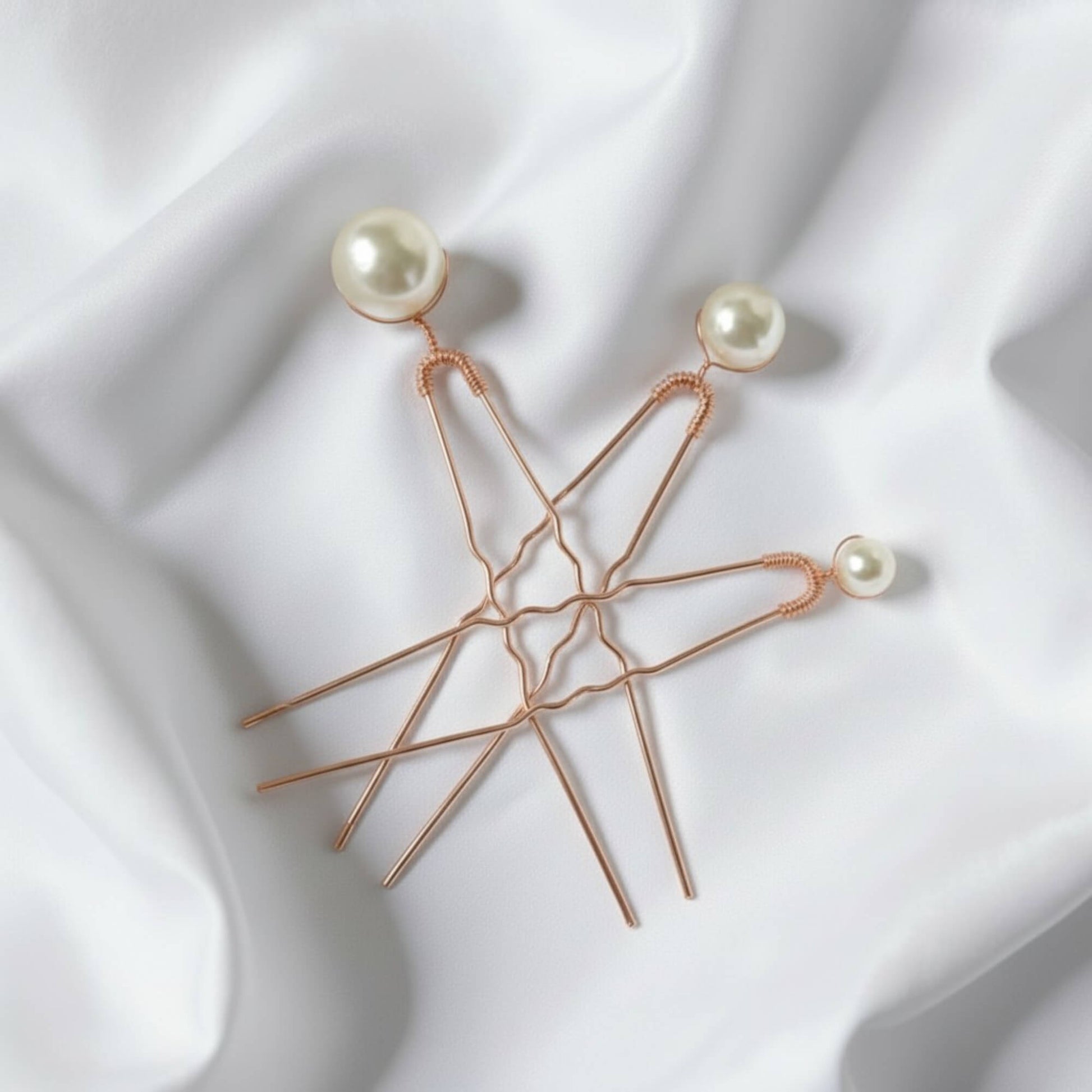 Set of three gold bridal hairpins with premium glass pearls on white silk background