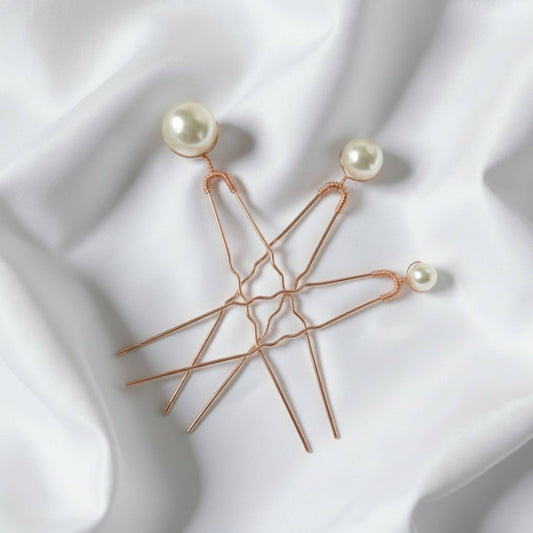 Set of three gold bridal hairpins with premium glass pearls on white silk background
