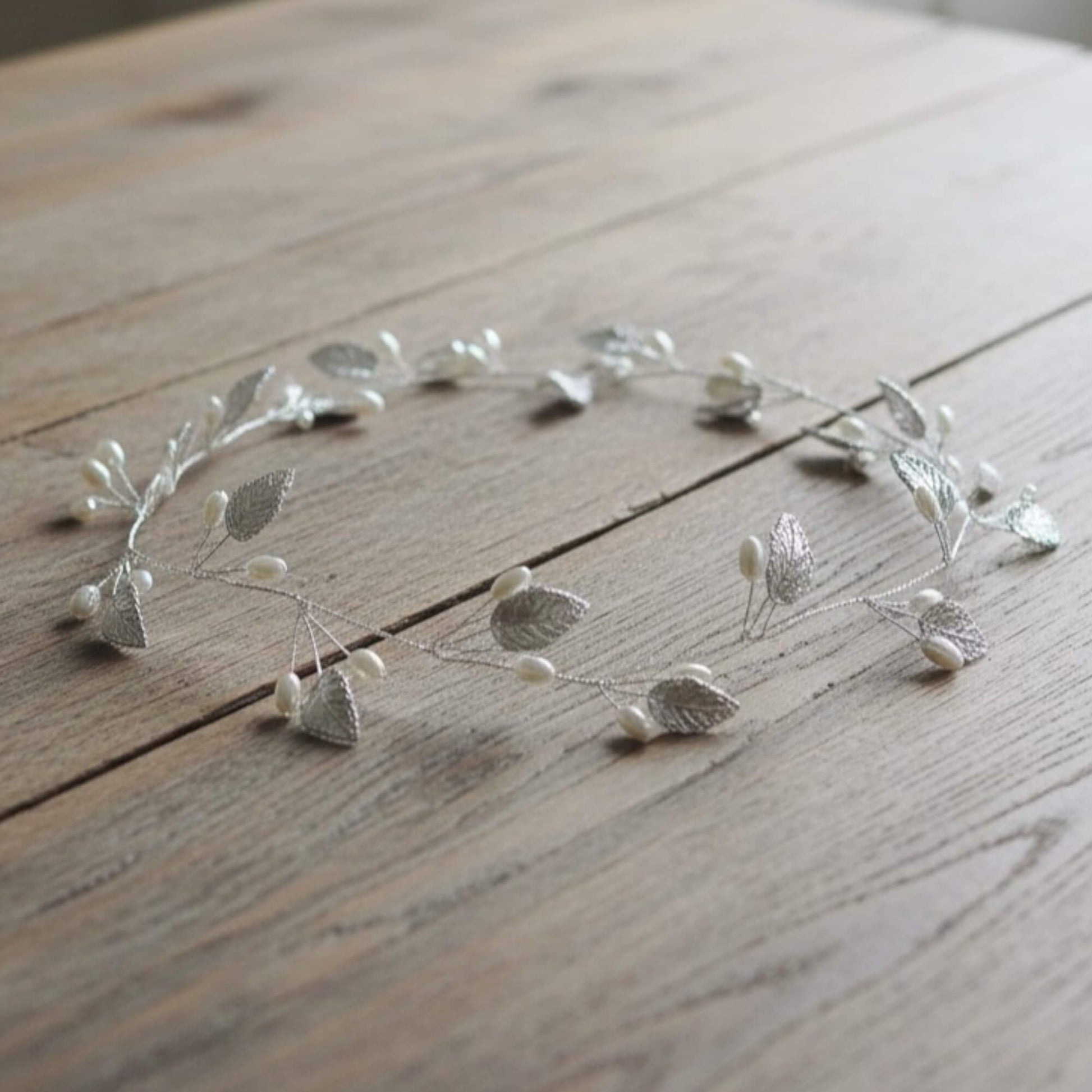 close up of silver wedding hair vine with pearl buds on wooden background
