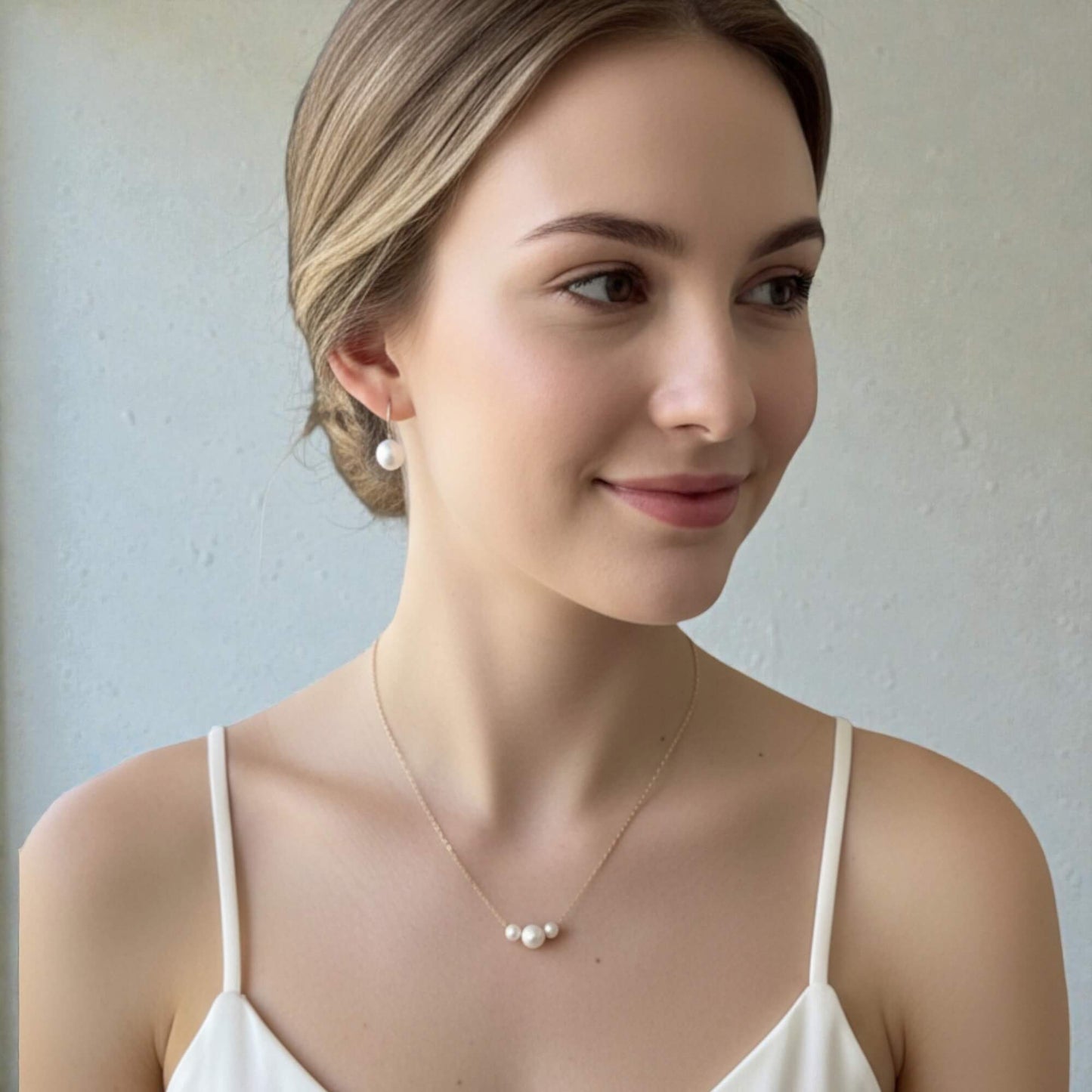 Woman wearing a pearl necklace and earrings against a plain background