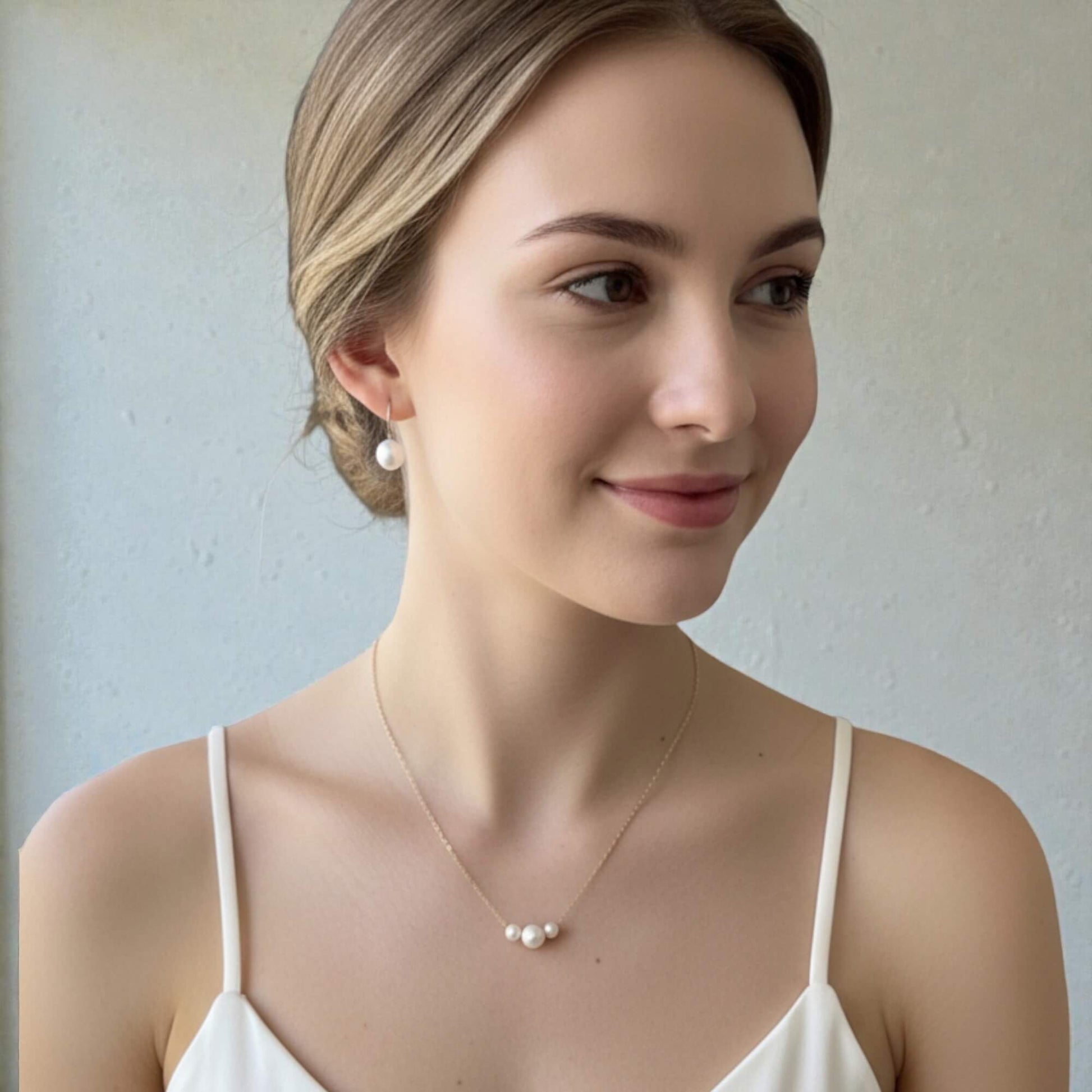 Woman wearing a pearl necklace and earrings against a plain background