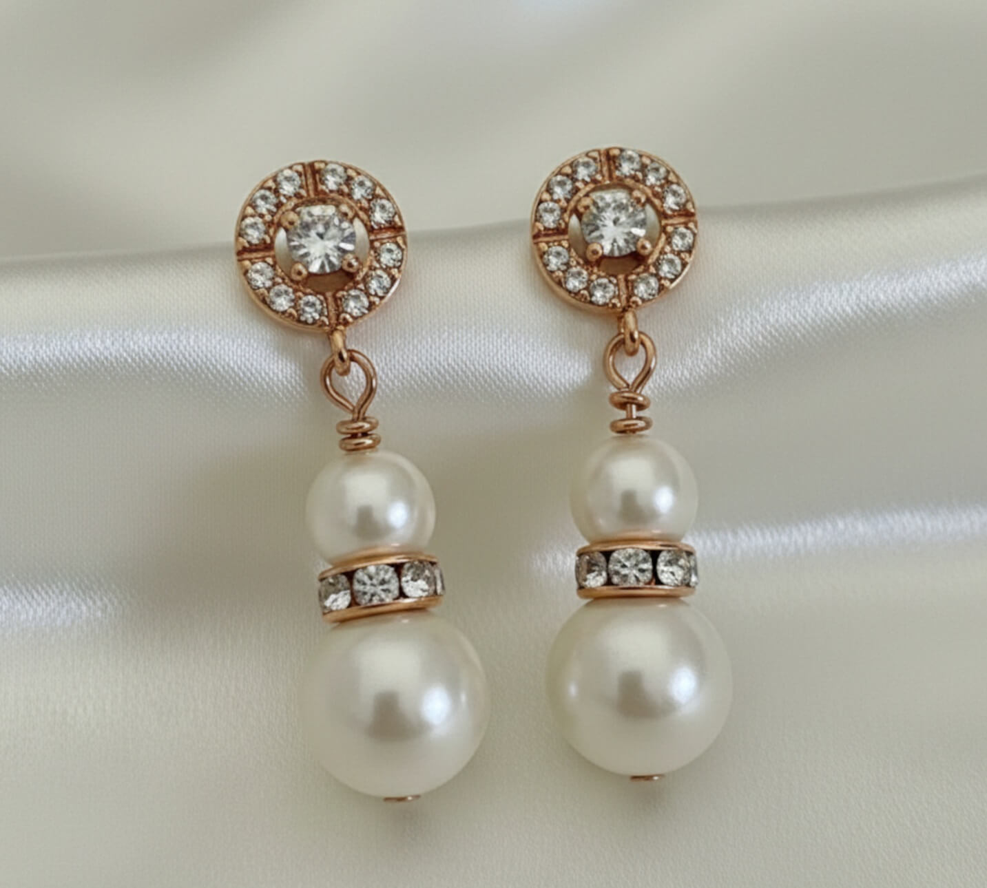 Gold and pearl bridal earrings with crystal halo, photographed on white silk flatlay